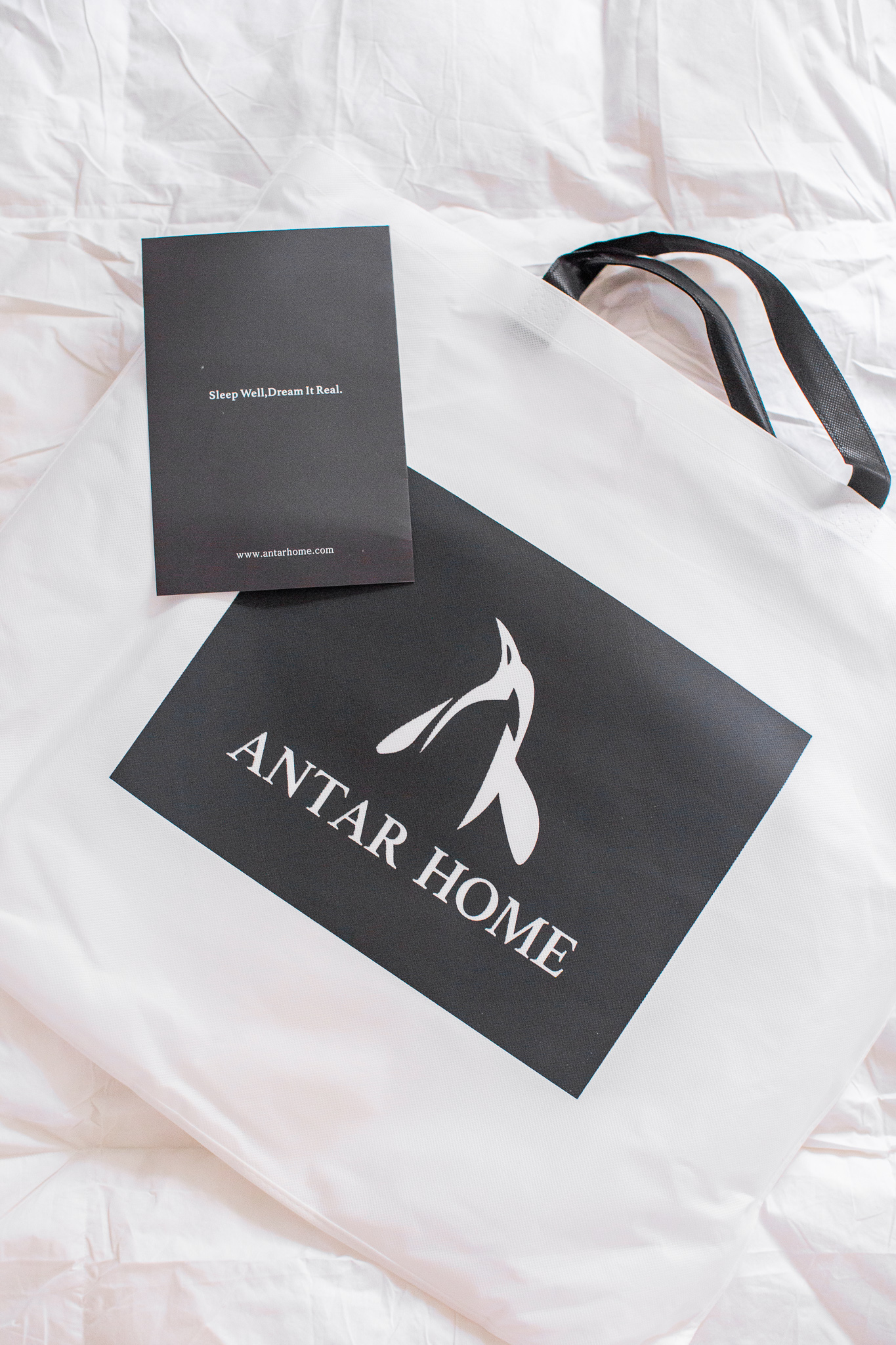 Modern Guest Bedroom Ideas with Antar-Home by popular North Carolina life and style blog, Coffee Beans and Bobby Pins: image of an Antar Home shopping bag on top of a white duvet.