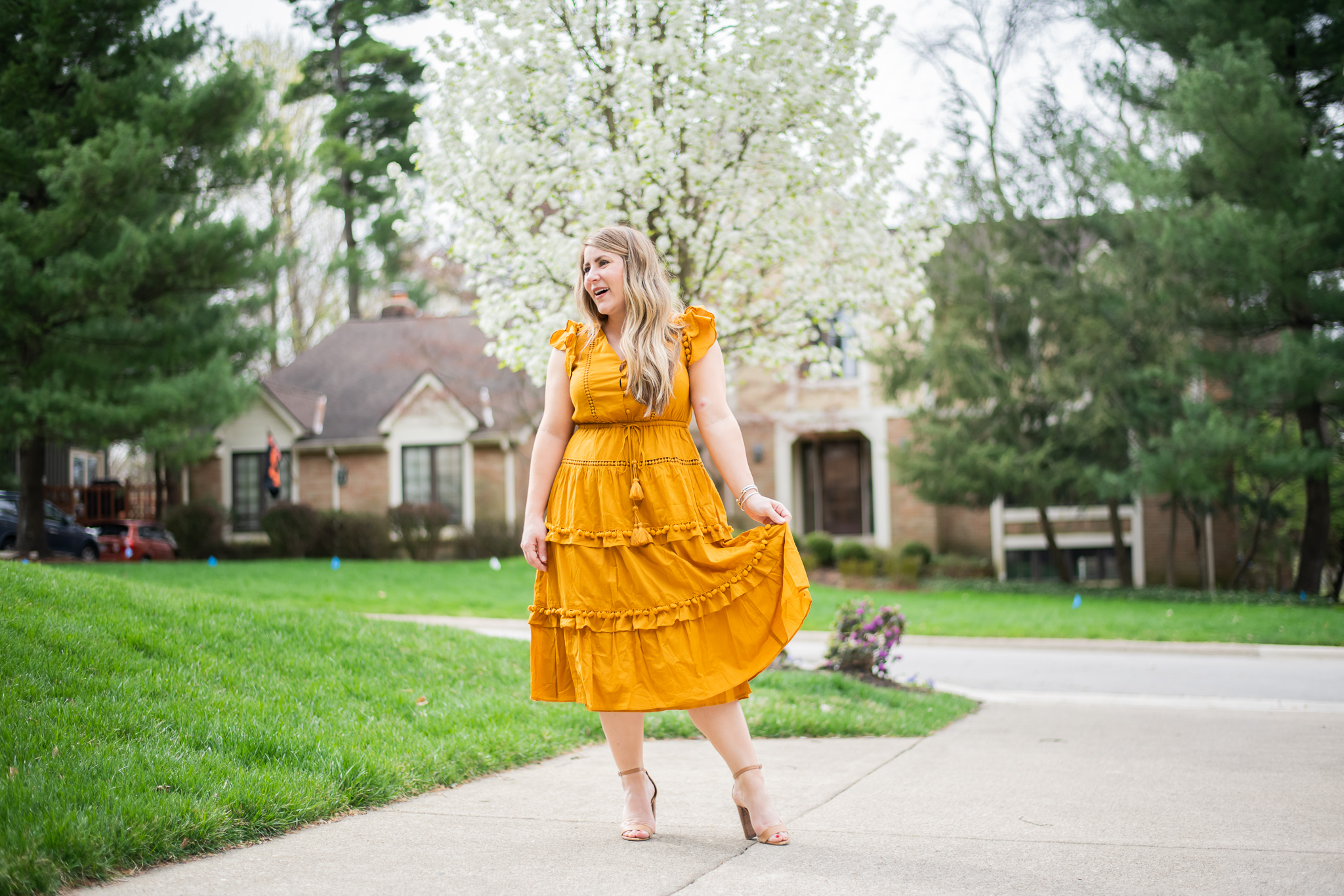 Summer Skin Care Tips with Cetaphil by popular North Carolina beauty blog, Coffee Beans and Bobby Pins: image of a woman wearing a mustard color dress and and standing outside by some trees with white blossoms on them.