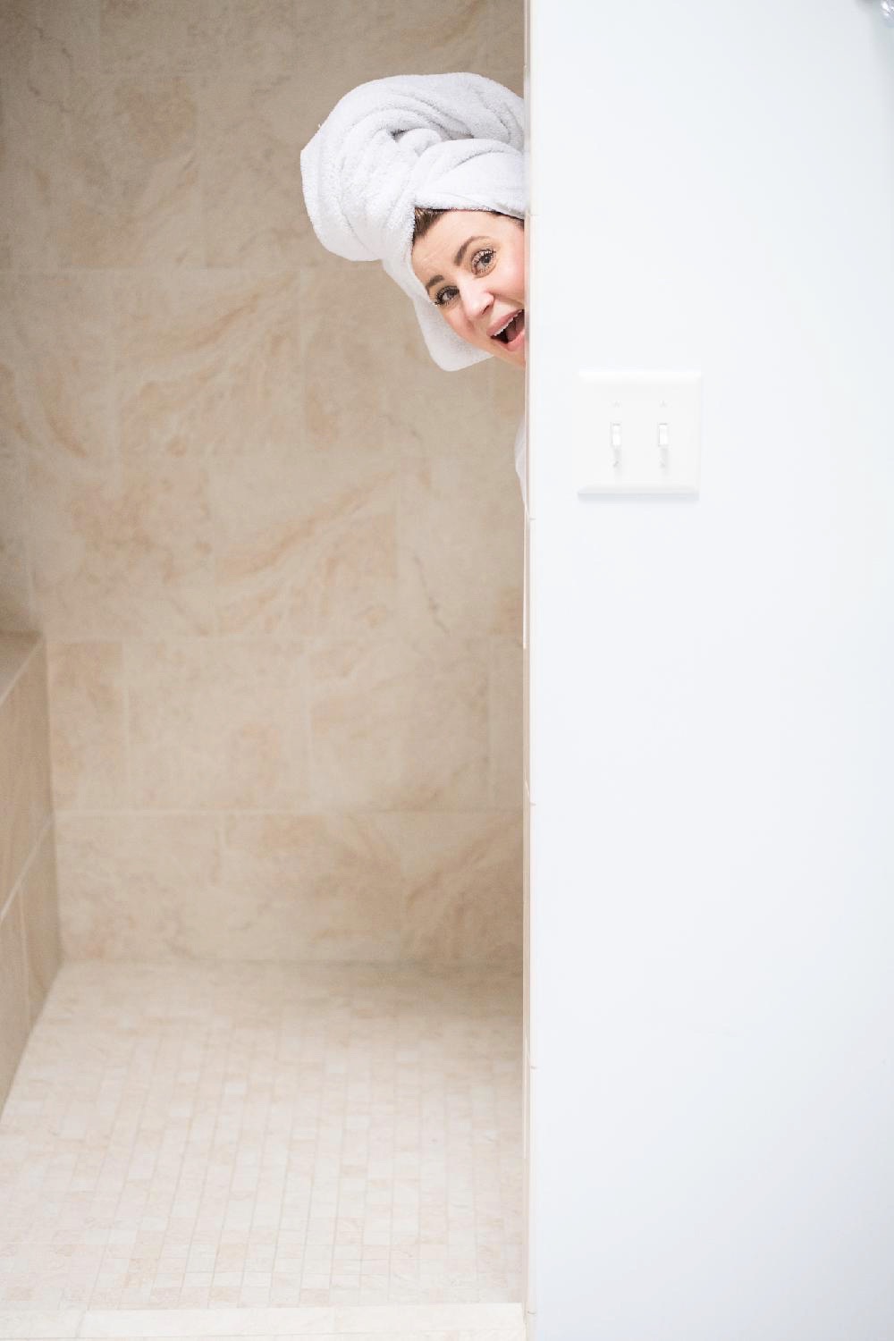 Summer Skin Care Tips with Cetaphil by popular North Carolina beauty blog, Coffee Beans and Bobby Pins: image of a woman poking her head  out from inside her walk-in shower.