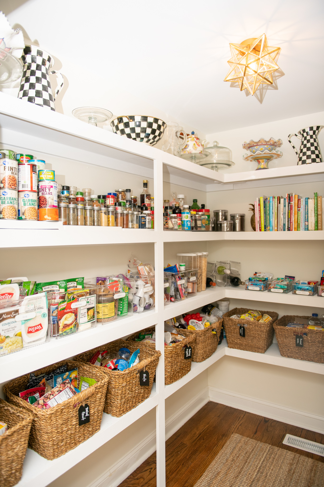 DIY Pantry Shelves by popular Ohio DIY lifestyle blog, Coffee Beans and Bobby Pins: image of a walk-in pantry with white shelves, a brown woven rug, brown wicker baskets, and a gold star pendant light. 