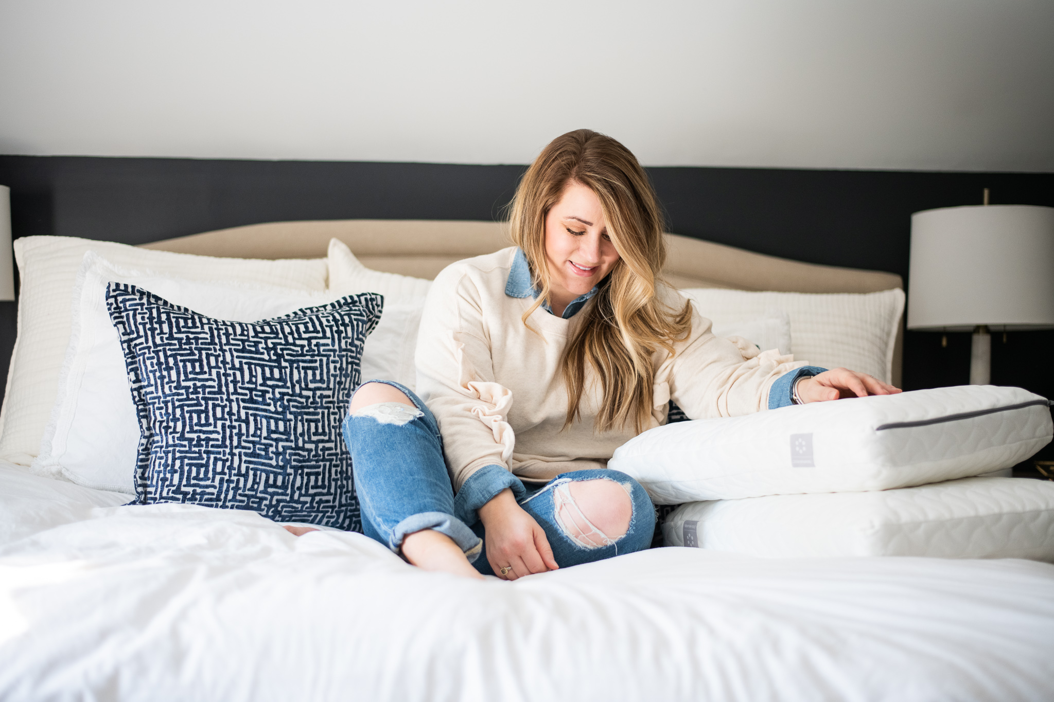 Tempur Pedic Pillows featured by top US lifestyle blog Coffee Beans and Bobby Pins; Image of woman sitting on her bed.