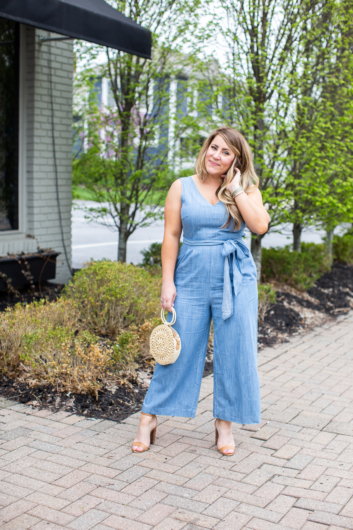 J.Crew Chambray Jumpsuit featured by top US fashion blog Coffee Beans and Bobby Pins; Image of a woman wearing a J.Crew jumpsuit, Steve Madden sandals, Target bag and Baublebar earrings.