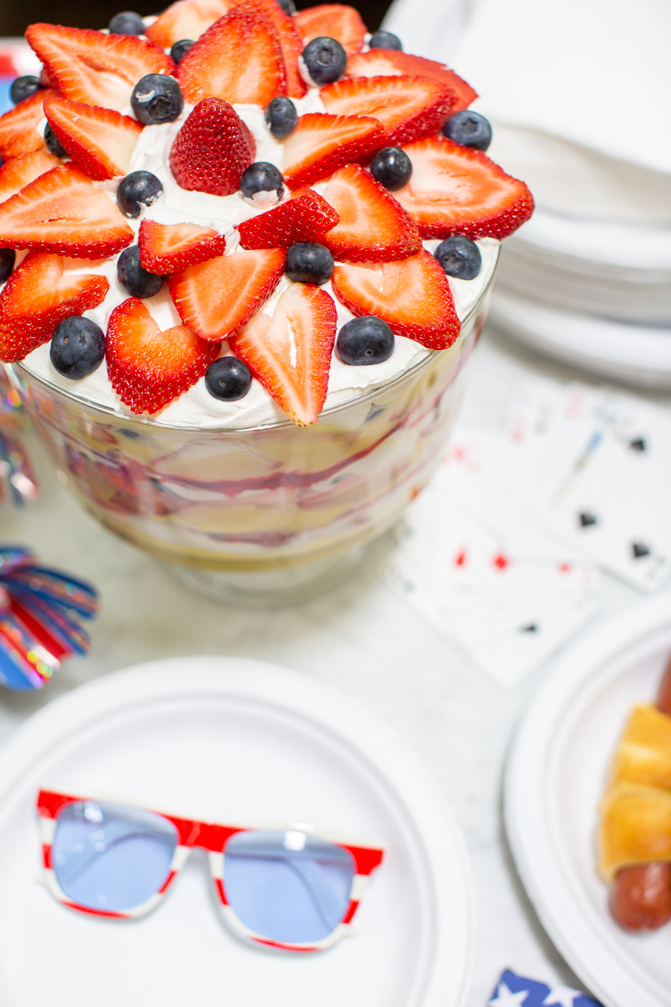 How to Throw the Ultimate (and Easy) 4th of July Party by popular North Carolina blog, Coffee Beans and Bobby Pins: image of chinet white paper plates, chinet white napkins, berry trifle, 4th of July sunglasses, face cards, and hot dogs.