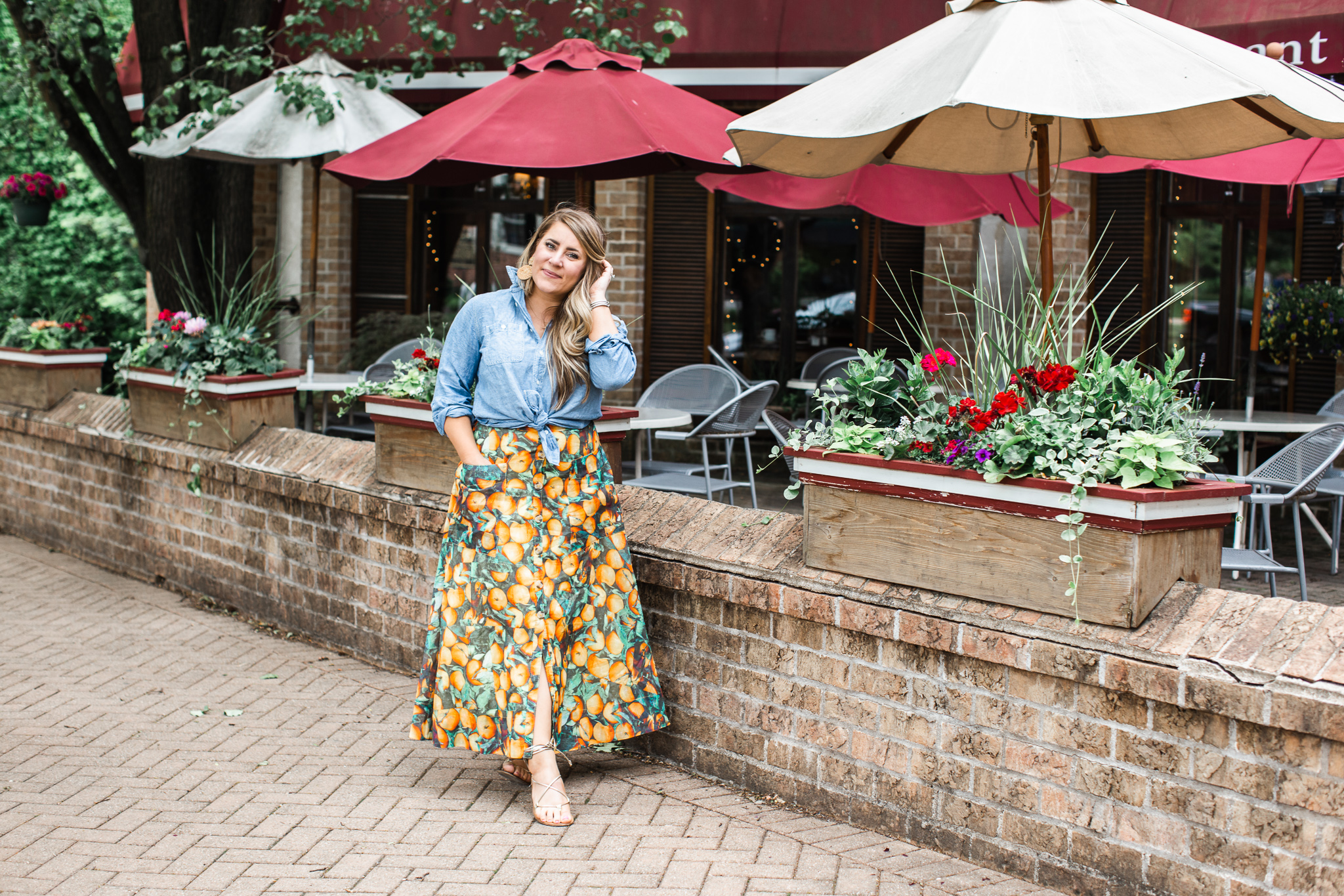 My Favorite Fruit Printed Anthropologie Maxi Skirt by popular North Carolina fashion blog, Coffee Beans and Bobby Pins: image of a woman standing outside of a restaurant and wearing a Anthropologie Summer Orchard Skirt, J. Crew Everyday chambray shirt, Madewell Coin Necklace Set, and DREAM PAIRS Women's Sammy Gladiator Lace up Flat Sandals.  