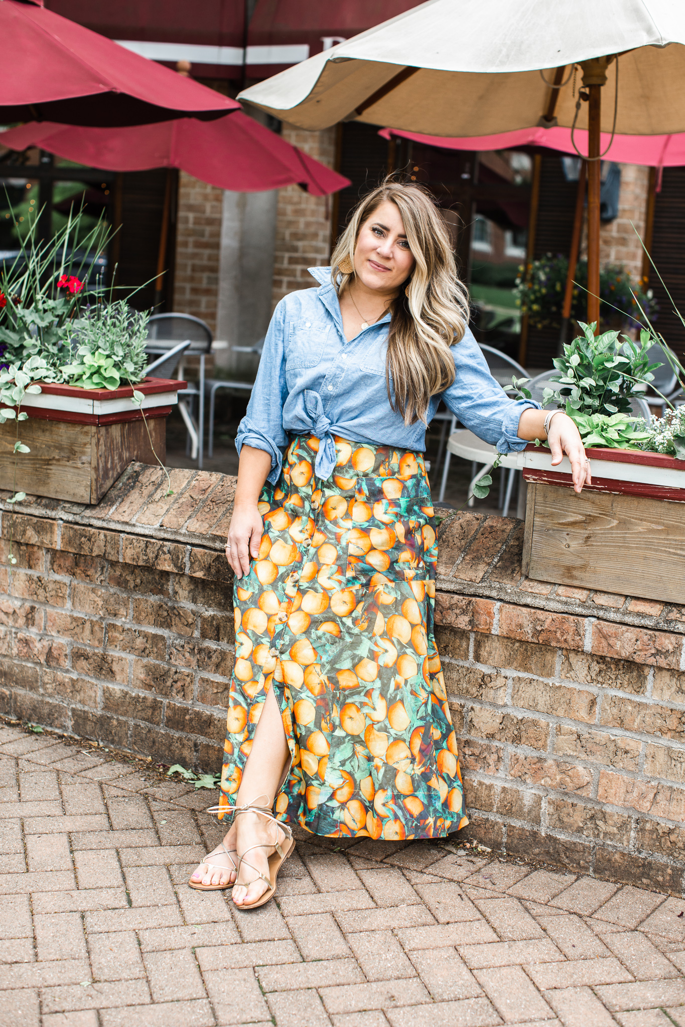 My Favorite Fruit Printed Anthropologie Maxi Skirt by popular North Carolina fashion blog, Coffee Beans and Bobby Pins: image of a woman standing outside of a restaurant and wearing a Anthropologie Summer Orchard Skirt, J. Crew Everyday chambray shirt, Madewell Coin Necklace Set, and DREAM PAIRS Women's Sammy Gladiator Lace up Flat Sandals.  