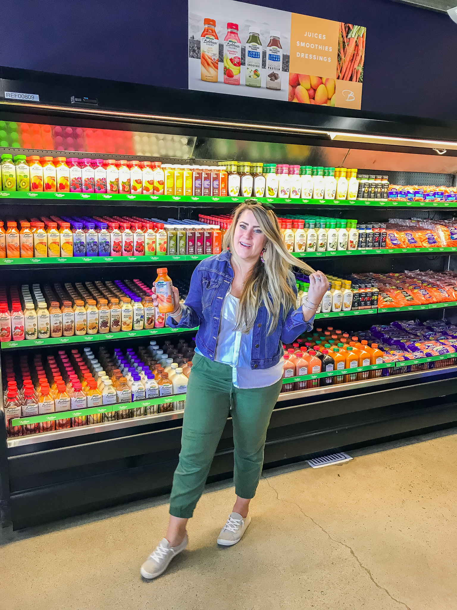 Bolthouse Farms Bakersfield Visit – Our California Trip Recap by popular North Carolina lifestyle blog, Coffee Beans and Bobby Pins: image of a woman inside a grocery store standing next to a bunch of Bolthouse Farms juices and holding a carrot juice in her hands.
