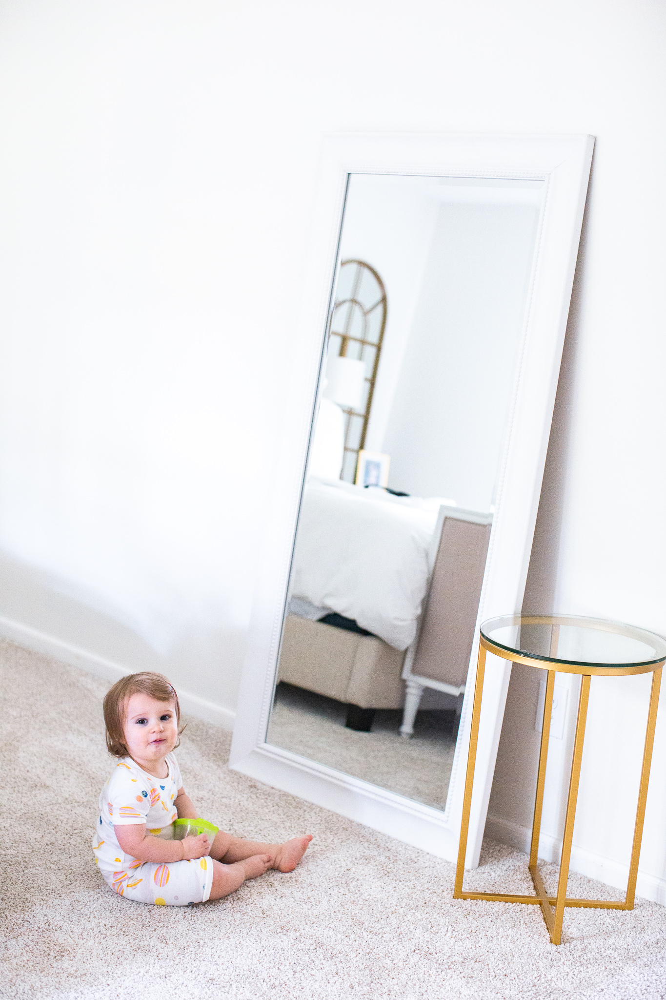 Modern Guest Bedroom Ideas with Antar-Home by popular North Carolina life and style blog, Coffee Beans and Bobby Pins: image of a baby girl sitting in front of a full length mirror in a guest bedroom.