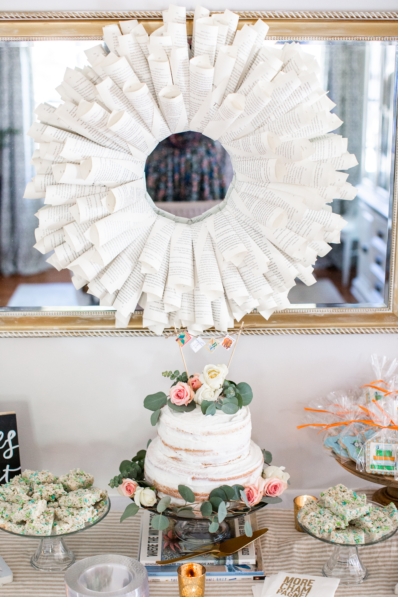  Story Book Baby Shower Ideas by popular North Carolina life and style blog, Coffee Beans and Bobby Pins: image of a two tier cake, rice krispie treats, candle votives, book worm cookies party favors, clear plastic plates, picture books, and a book page wreath.