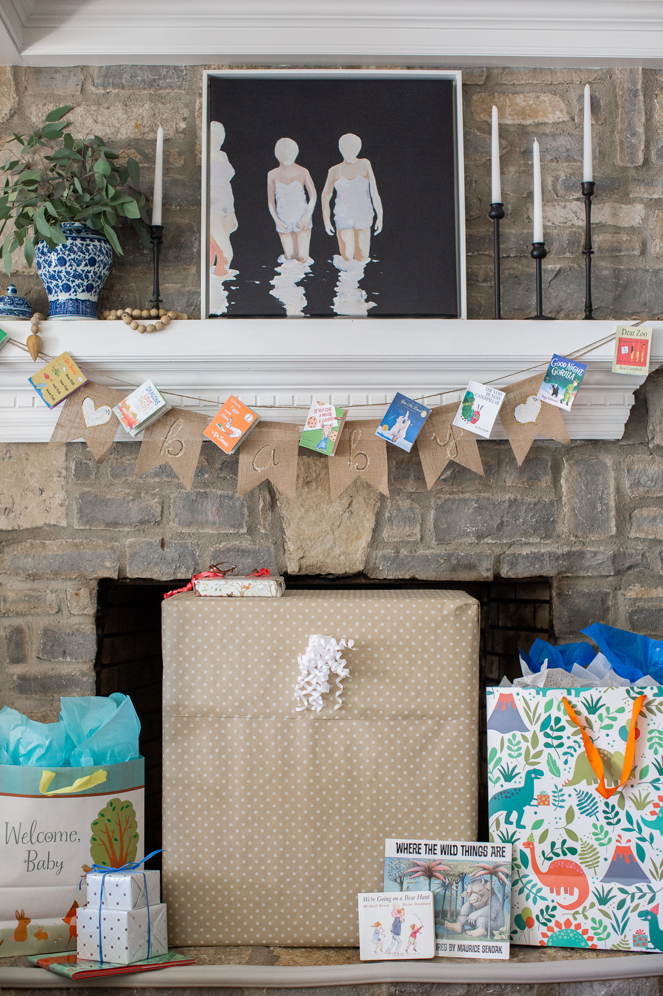  Story Book Baby Shower Ideas by popular North Carolina life and style blog, Coffee Beans and Bobby Pins: image of a children's picture book banner hanging on a fireplace mantle with presents stacked up in a pile below.