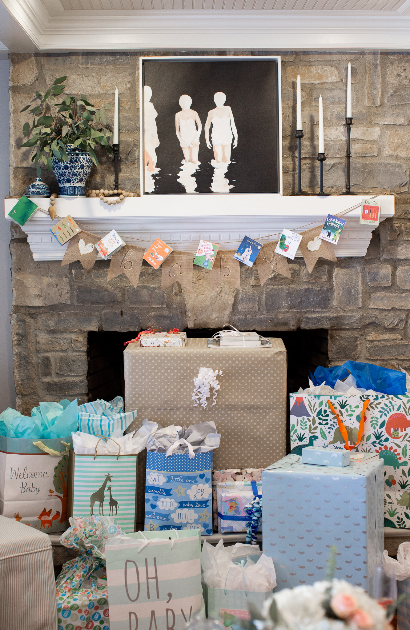  Story Book Baby Shower Ideas by popular North Carolina life and style blog, Coffee Beans and Bobby Pins: image of a children's picture book banner hanging on a fireplace mantle with presents stacked up in a pile below.