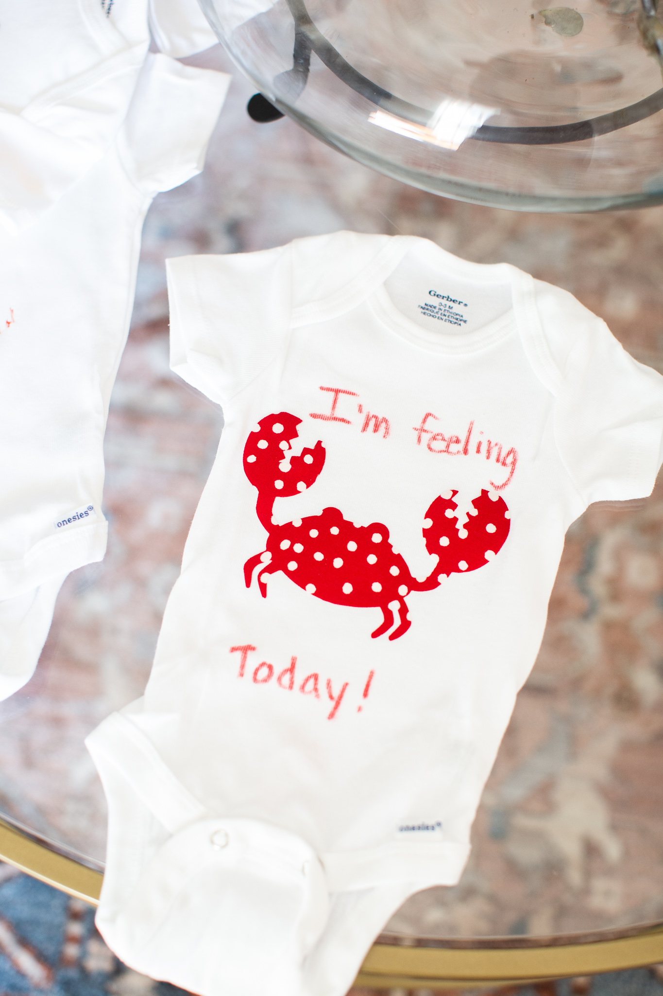  Story Book Baby Shower Ideas by popular North Carolina life and style blog, Coffee Beans and Bobby Pins: image of a decorated onesie with a crab on it.