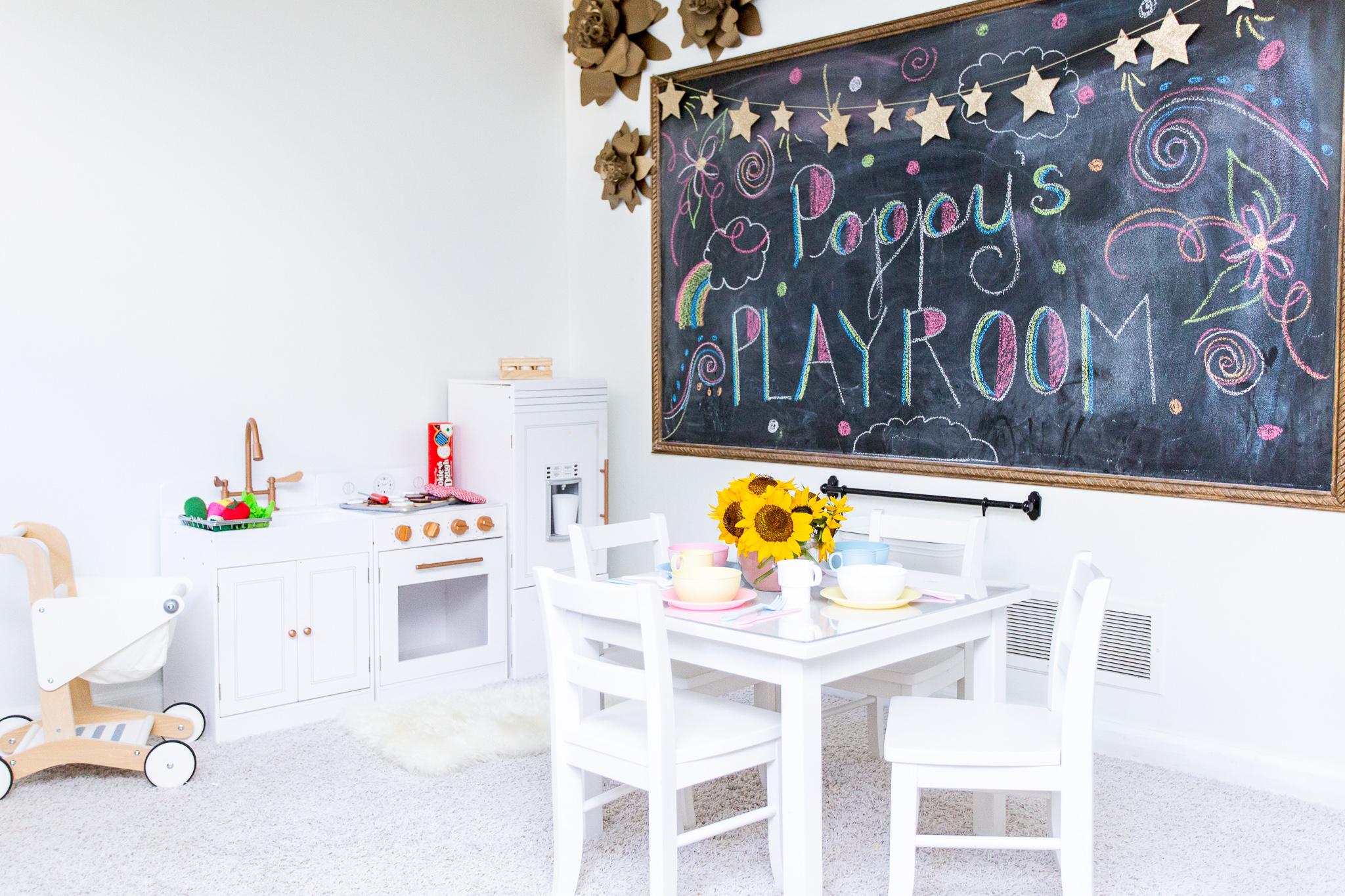 Playroom Storage Ideas and How I Combat All the Toys by popular North Carolina lifestyle blog, Coffee Beans and Bobby Pins: image of a playroom with a play kitchen, chalk board, wooden shopping cart, and play table.