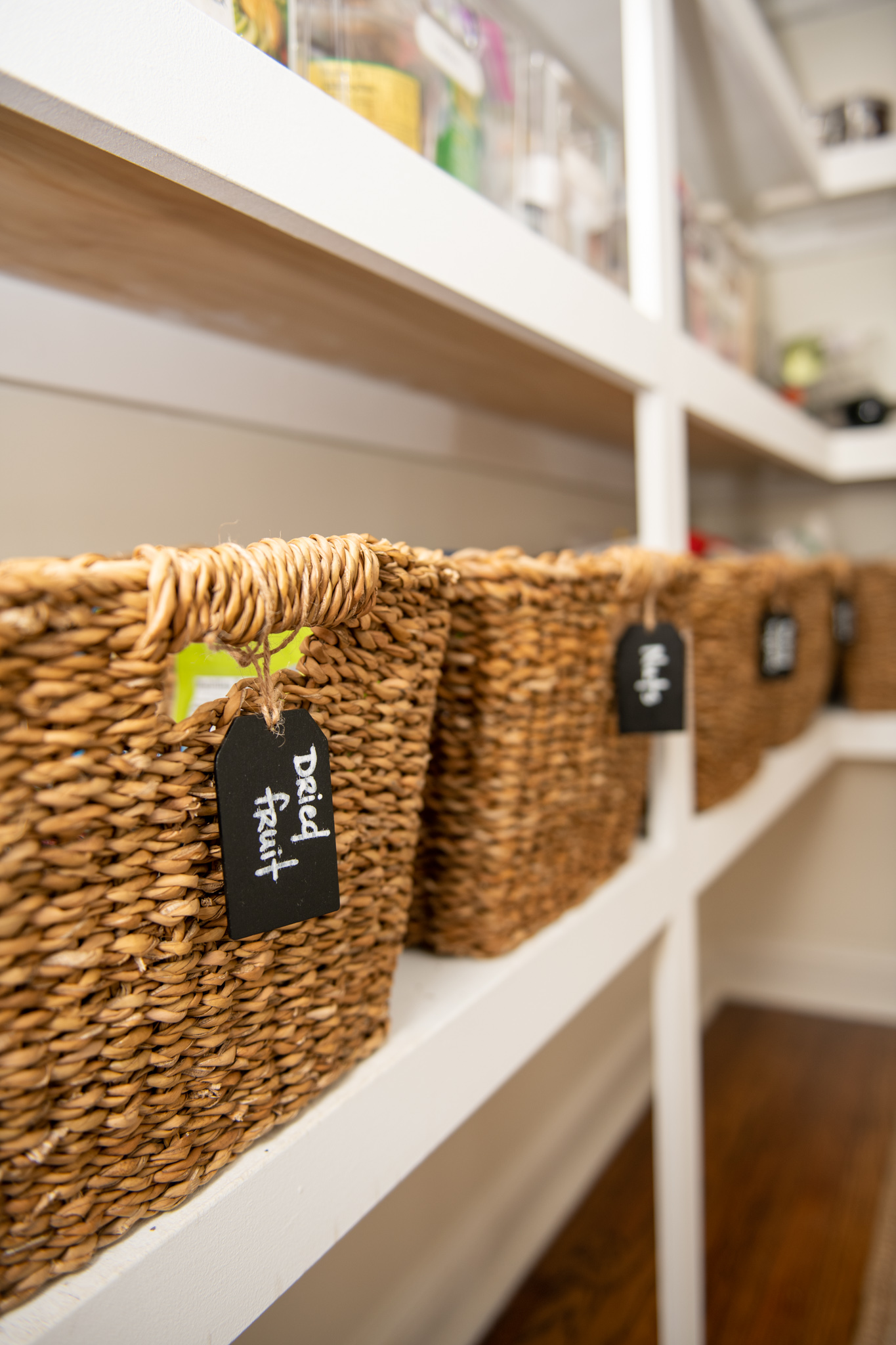 Pantry Organization Hacks by popular Ohio lifestyle blog, Coffee Beans and Bobby Pins: image of an organized pantry with The Container Store Tapered Hogla Storage Bin with Handles that have chalkboard tags hanging from each handle. 