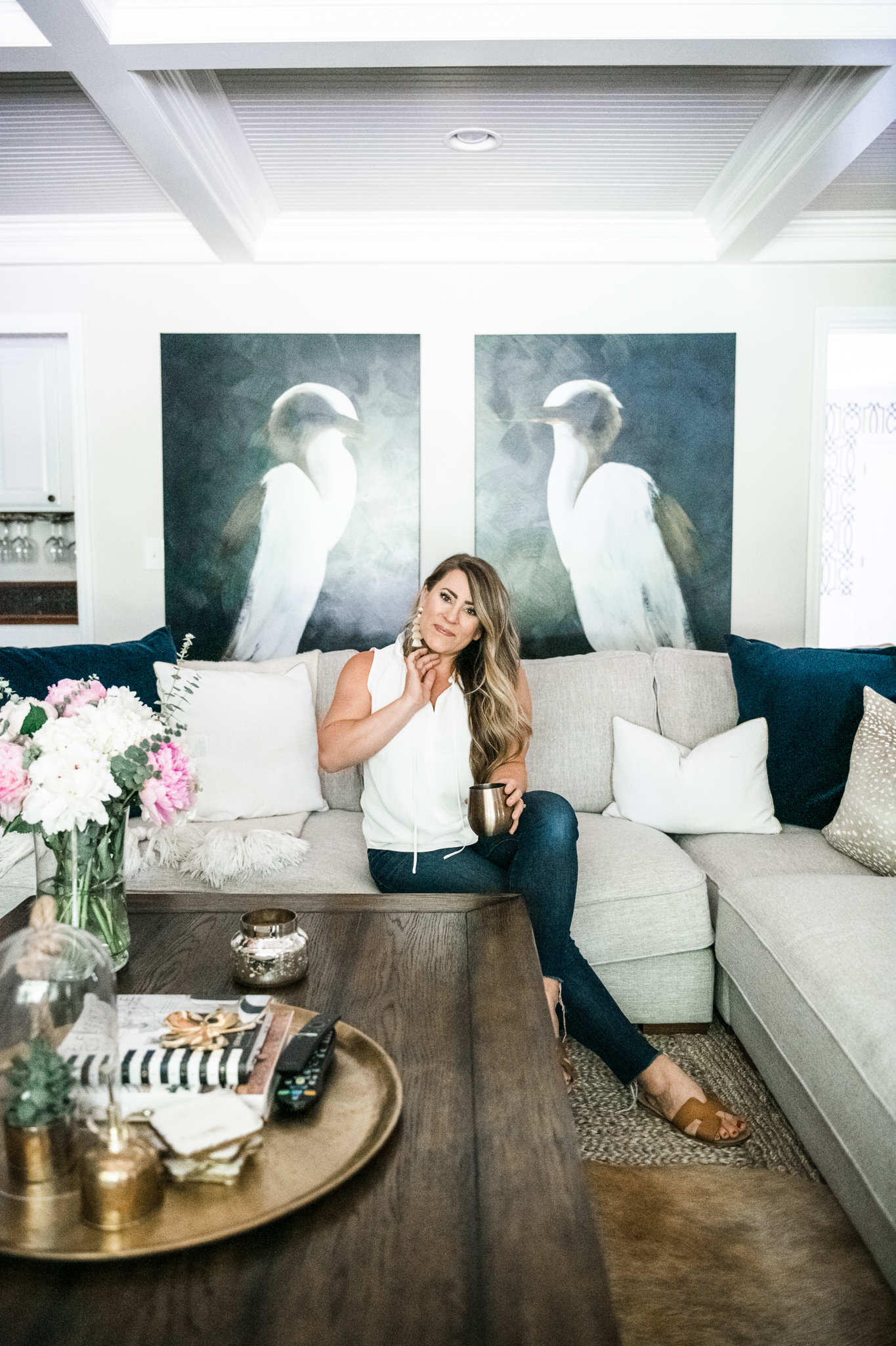 Grandin Road Wall Art by popular Ohio life and style blog, Coffee Beans and Bobby Pins: image of a woman sitting on a grey sectional couch in her living room in front of a pair of Grandin Road White Heron Wall Art.
