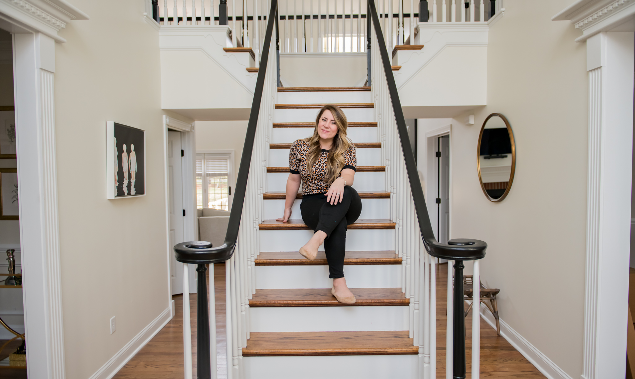 DIY Stair Railing Makeover by popular Ohio DIY blog, Coffee Beans and Bobby Pins: image of a woman sitting on her stairs and wearing a Ann Taylor Leopard Print Puff Sleeve Sweater and J. Crew Factory 8" midrise skinny jean in black denim.