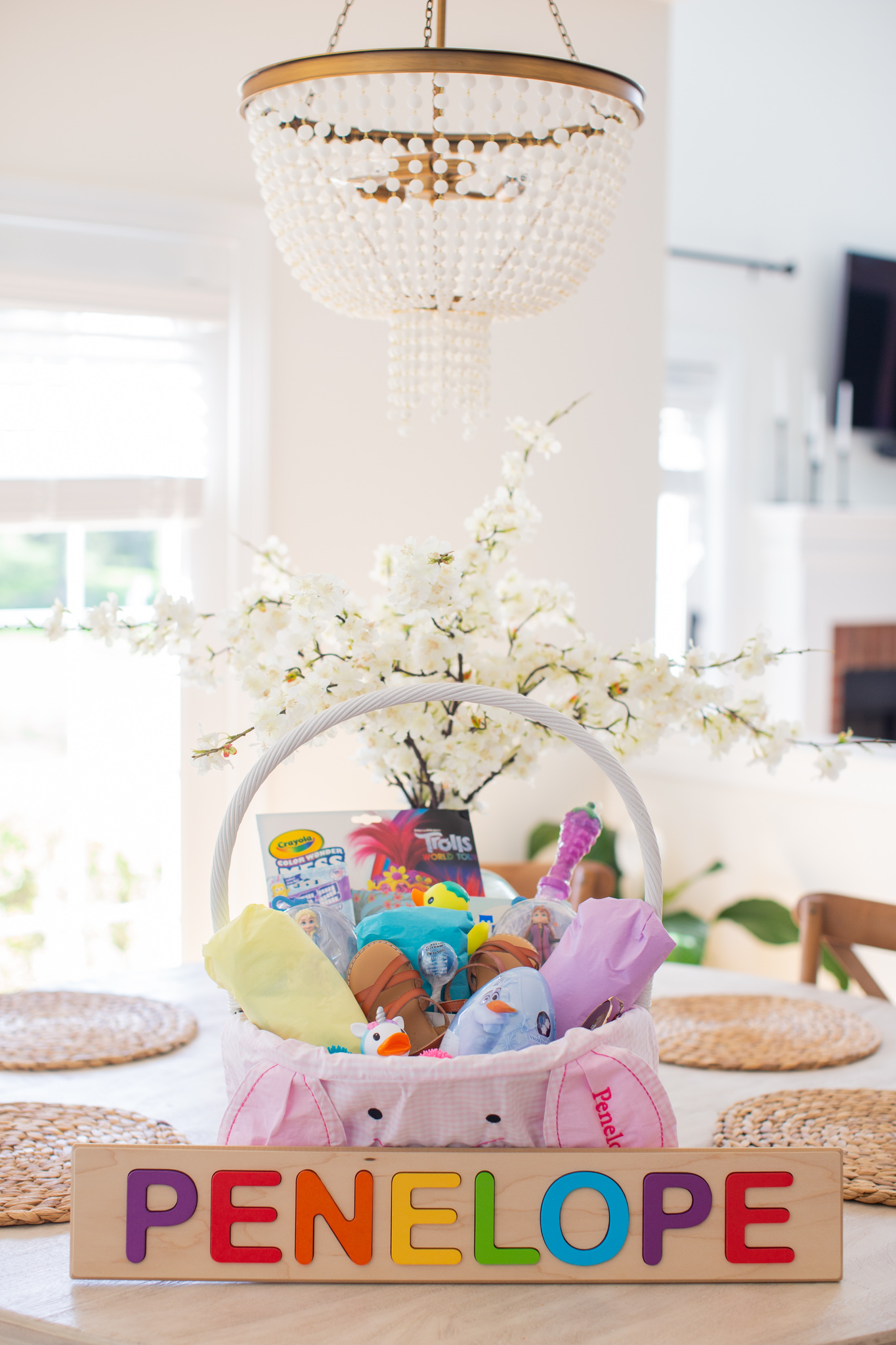 Toddler Easter Basket by popular Ohio lifestyle blog, Coffee Beans and Bobby Pins: image of a white wicker basket with a Pottery Barn Kids Gingham Bunny Face Easter Basket Liner, Amazon Fat Brain Toys Wooden Personalized Name Puzzle, Target Munchkin White Hot Safety Bath Ducky, Target Little Kids Fubble Bubble Wand, Target Cat and Jack sandals, Target Girls' Heart Shape Aviator Sunglasses and Amazon Crayola Baby Shark Color Wonder Coloring Pages.