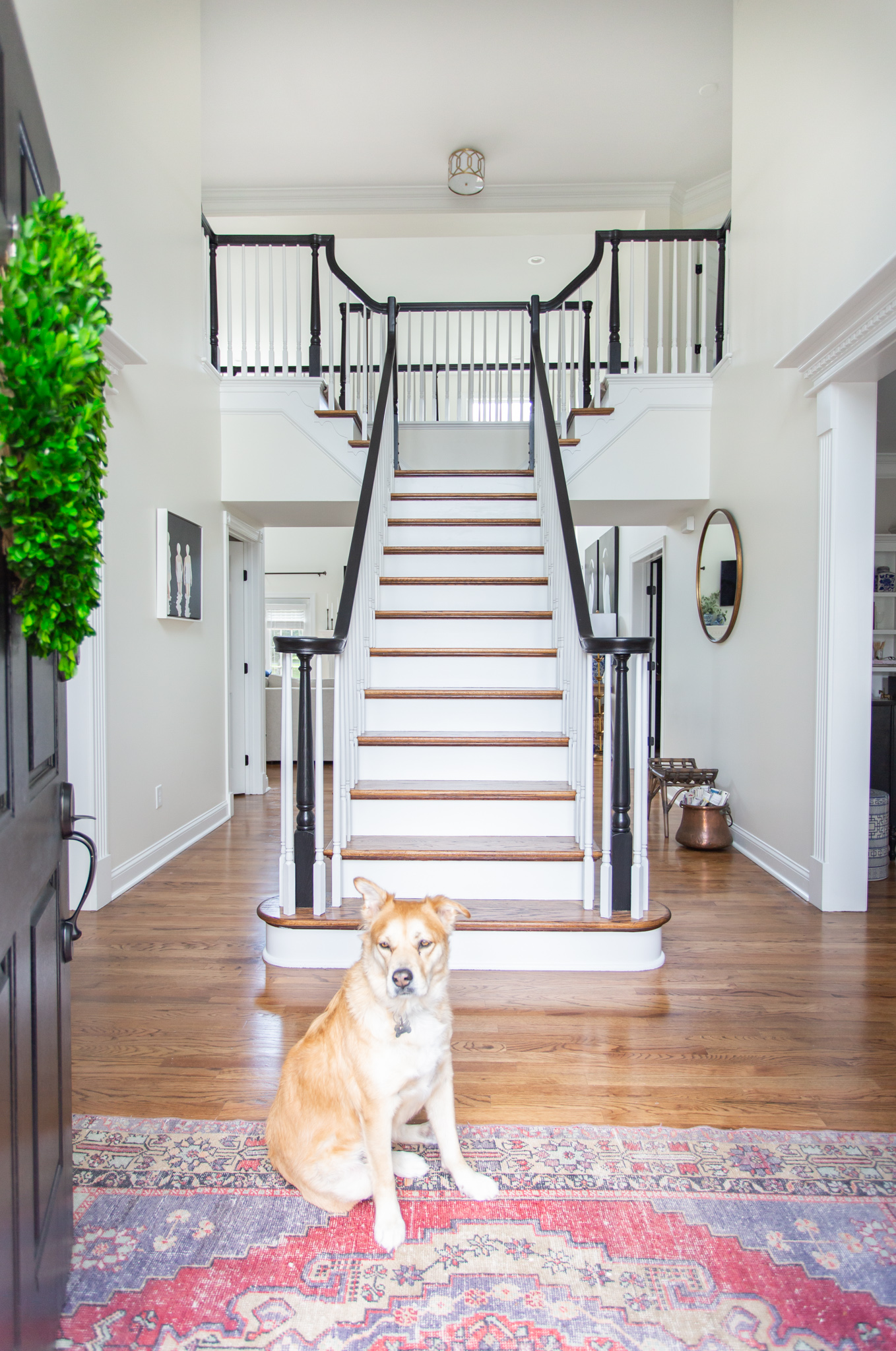 DIY Stair Railing Makeover by popular Ohio DIY blog, Coffee Beans and Bobby Pins: after image of a painted and renovated staircase with a dog sitting at the base of the stairs. 