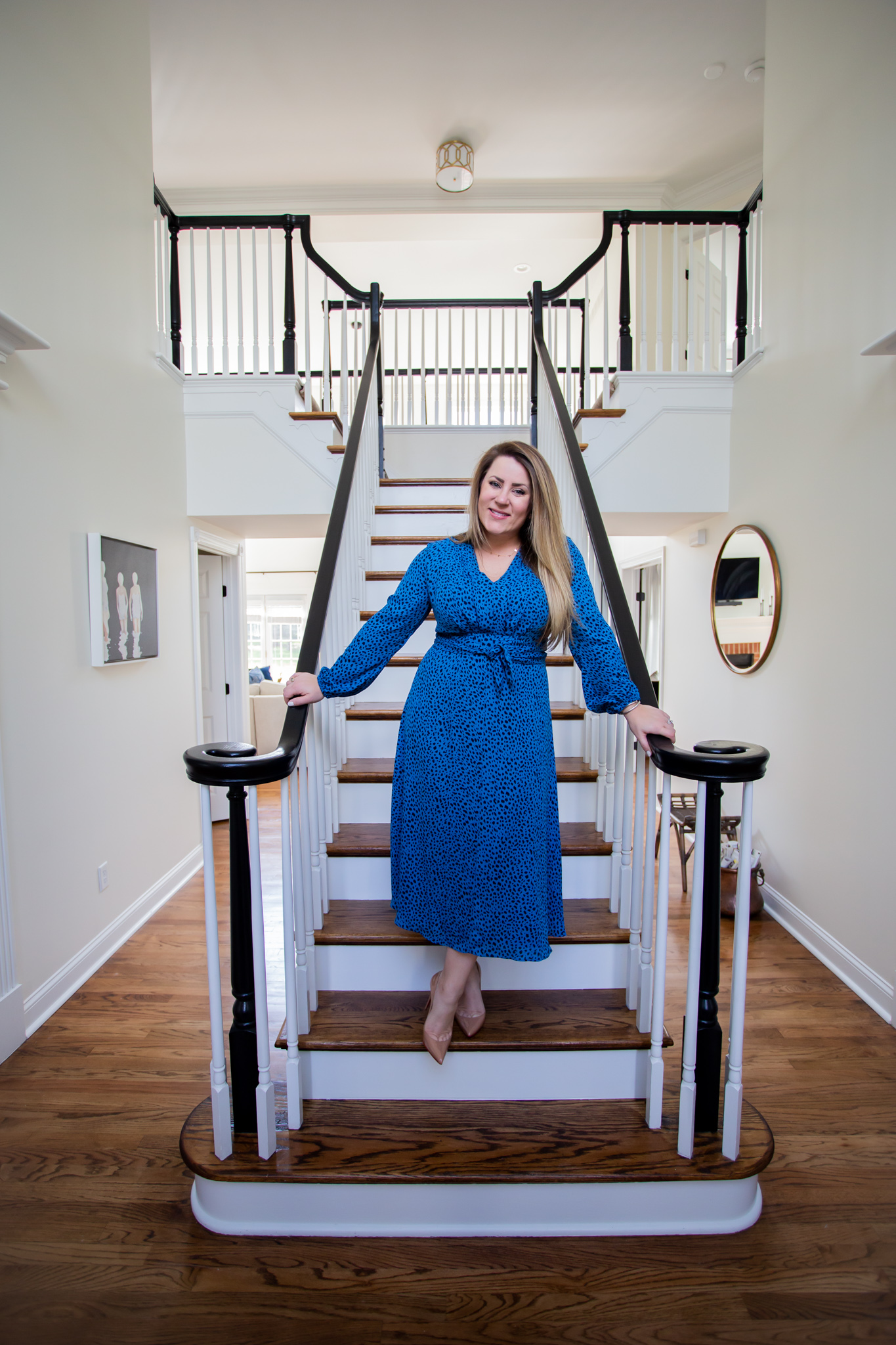 Arhaus Lighting by popular Ohio life and style blog, Coffee Beans and Bobby Pins: image of a woman wearing a blue and black leopard print dress and standing on her staircase. 