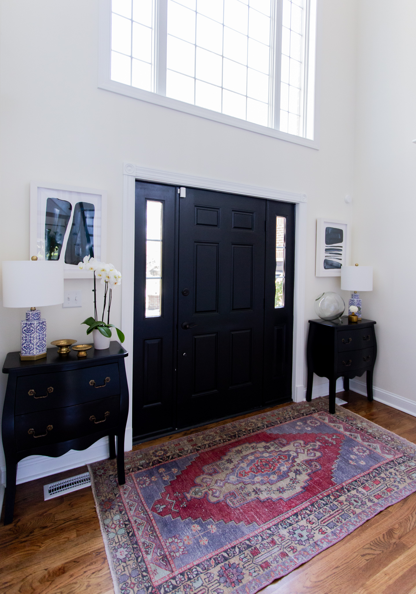 Arhaus Lighting by popular Ohio life and style blog, Coffee Beans and Bobby Pins: image of a entry way decorated with a Arhaus poppy large chandelier, Arhaus rug, Arhaus black lines framed print 1, Arhaus bombay small chest, and Arhaus lotus bud vase.