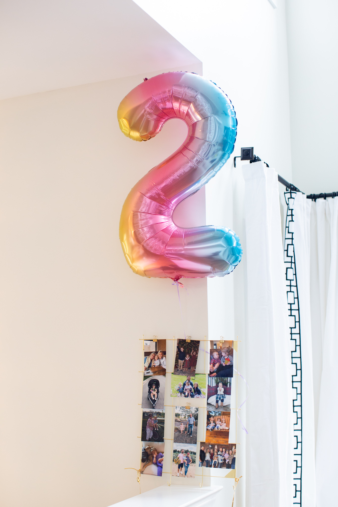 2nd Birthday Party Ideas by popular Ohio lifestyle blog, Coffee Beans and Bobby Pins: image of a rainbow colored number 2 Mylar balloon floating above a picture collage. 