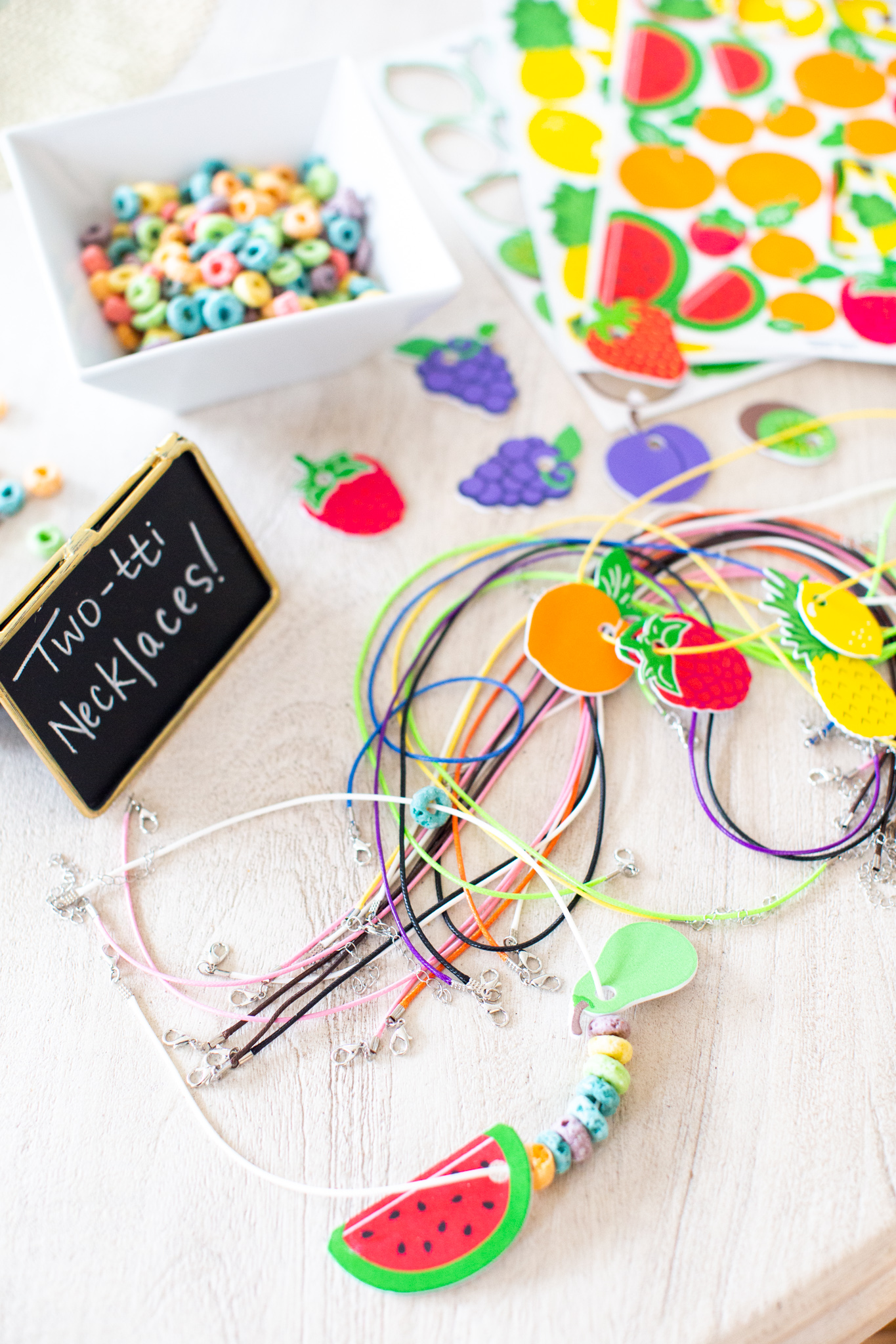 2nd Birthday Party Ideas by popular Ohio lifestyle blog, Coffee Beans and Bobby Pins: image of necklaces decorated with fruit loops and die cut pieces of paper fruit. 
