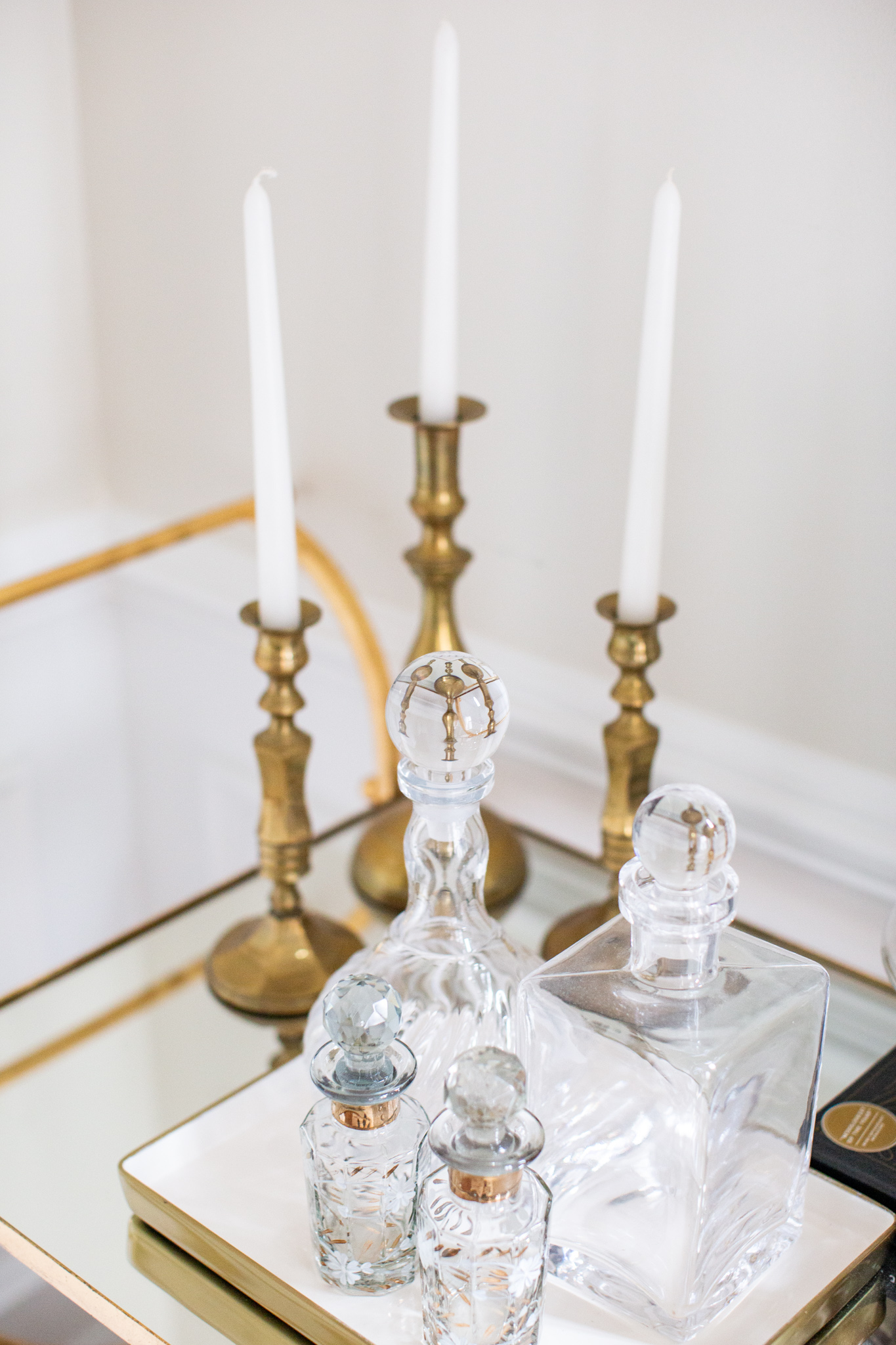 Mixing Old and New Furniture by popular Ohio life and style blog, Coffee Beans and Bobby Pins: image of a bar cart with old and new candle holders and candle stick and old and new decanters. 