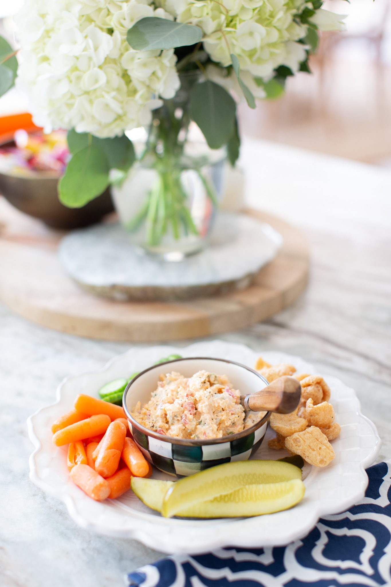 Jalapeno Pimento Cheese by popular Ohio food blog, Coffee Beans and Bobby Pins: image of a white plate with a bowl of jalapeno pimento cheese, baby carrots, English cucumber slices, pickle spears, and chips. 