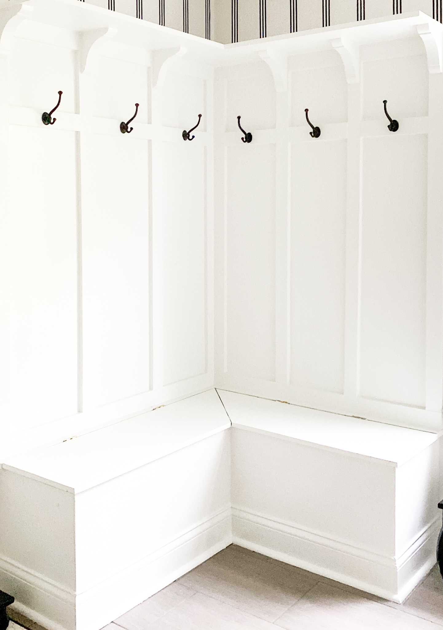 One Room Challenge by popular life and style blog, Coffee Beans and Bobby Pins: image of a white mudroom bench with overhead shelving and black metal wall hooks. 