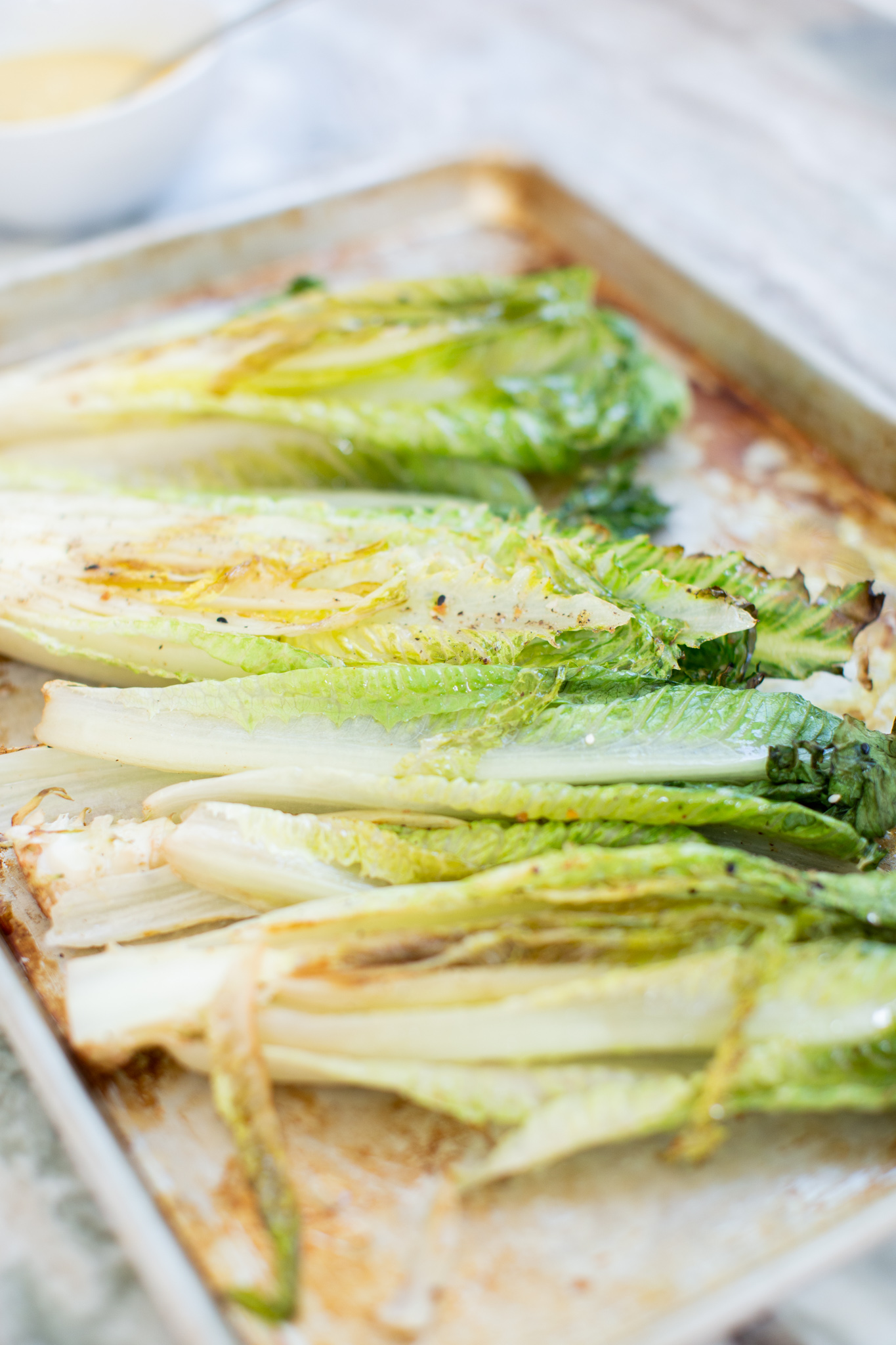 Grilled Romaine Salad by popular Ohio lifestyle blog, Coffee Beans and Bobby Pins: image of grilled romaine lettuce on a cookie sheet. 