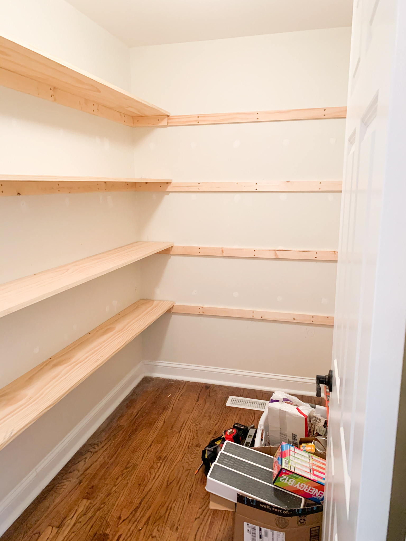 DIY Pantry Shelves by popular Ohio DIY lifestyle blog, Coffee Beans and Bobby Pins: image of a walk-in pantry with wooden shelving. 