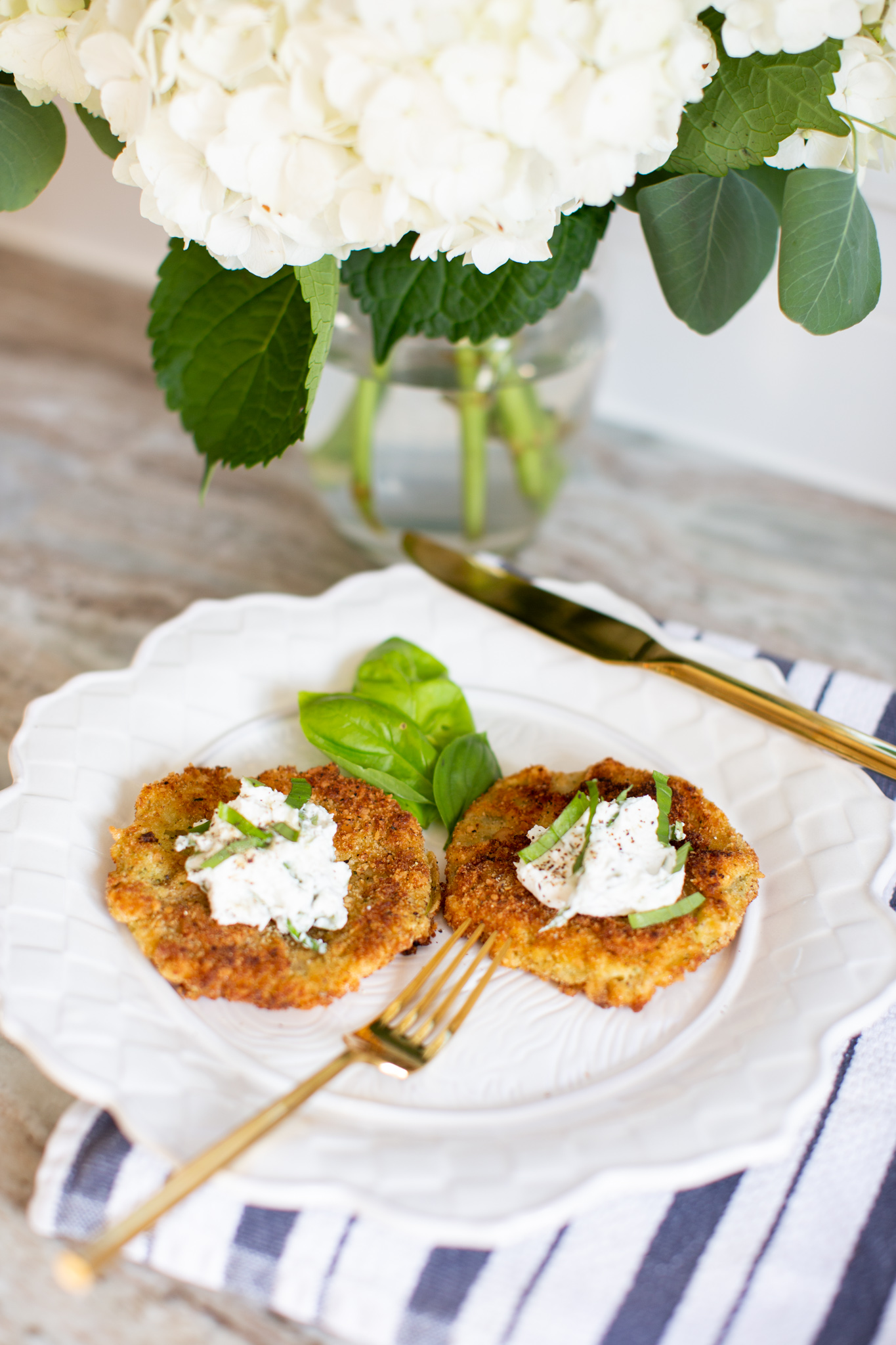 Fried Green Tomatoes by popular Ohio life and style blog, Coffee Beans and Bobby Pins: image of fried green tomatoes with goat cheese whip on a white ceramic plate next to a gold fork. 