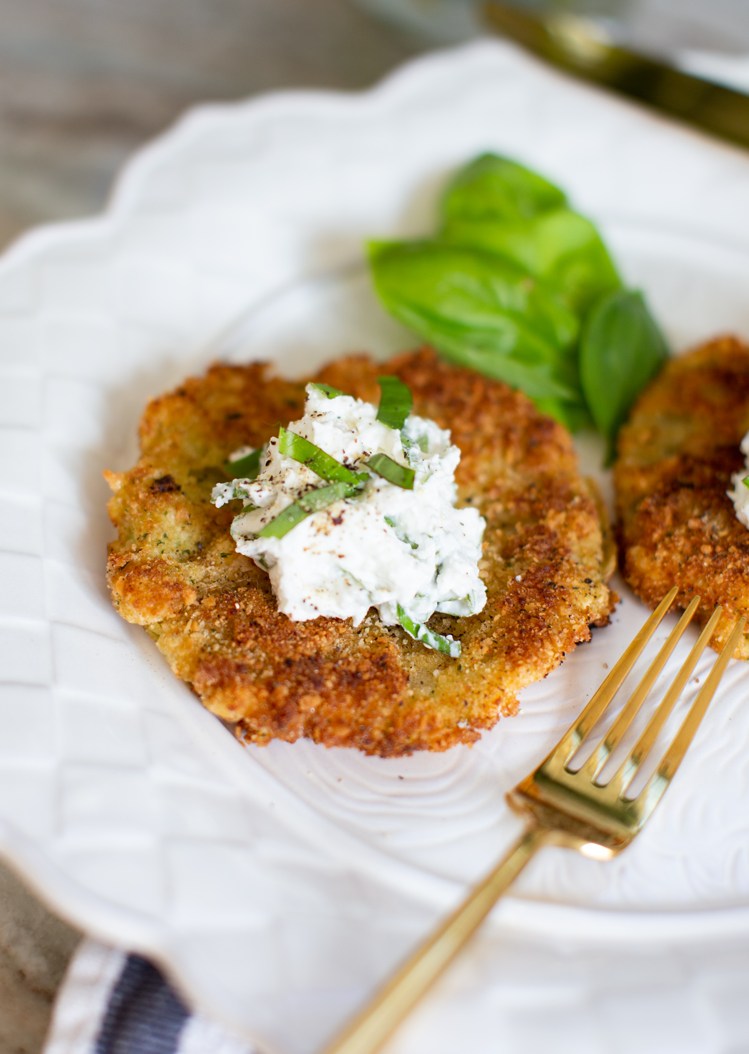 Fried Green Tomatoes by popular Ohio life and style blog, Coffee Beans and Bobby Pins: image of fried green tomatoes with goat cheese whip on a white ceramic plate next to a gold fork. 