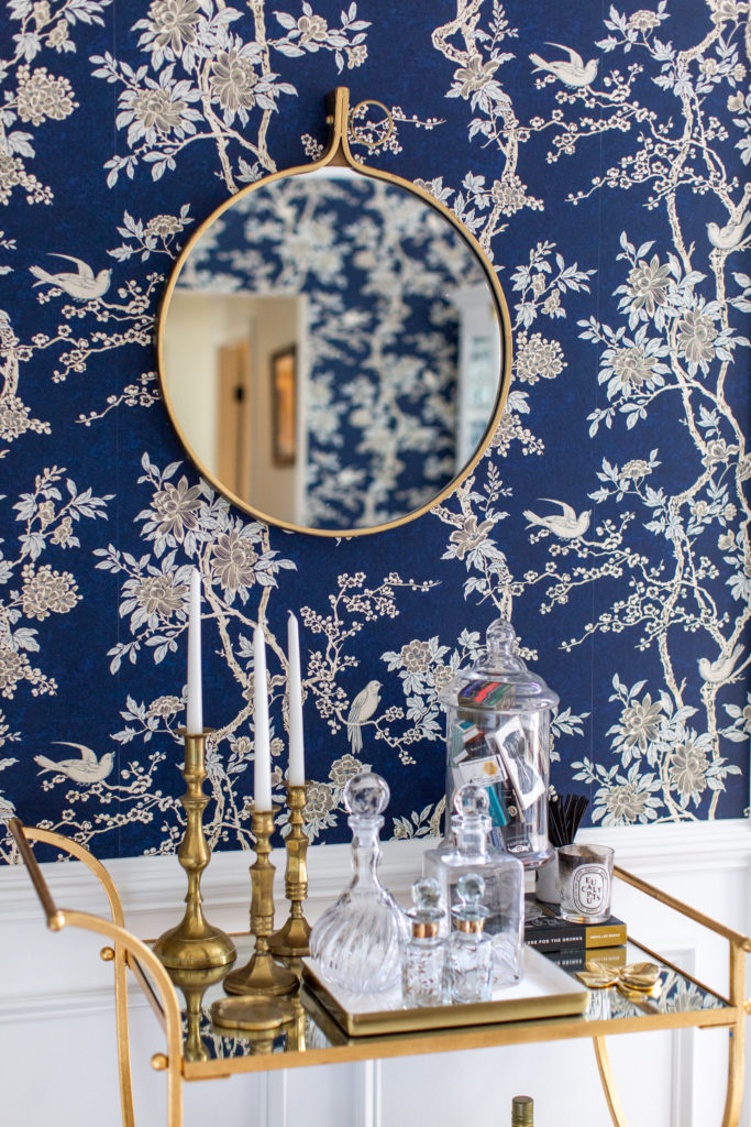 Blue Floral Wallpaper by popular Ohio life and style blog, Coffee Beans and Bobby Pins: image of a dining room with blue floral wallpaper and a gold bar cart with gold candle stick holders and apothecary jars on it. 