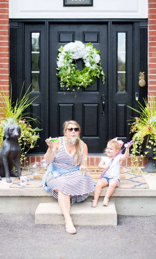 Deep Clean by popular Ohio lifestyle blog, Coffee Beans and Bobby Pins: image of a mom and daughter sitting on their front porch and blowing bubbles. 