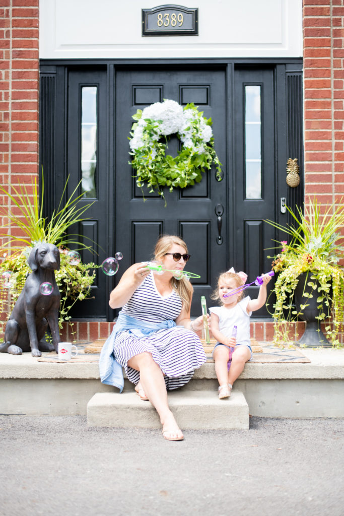 Deep Clean by popular Ohio lifestyle blog, Coffee Beans and Bobby Pins: image of a mom and daughter sitting on the front porch of their home and blowing bubbles. 