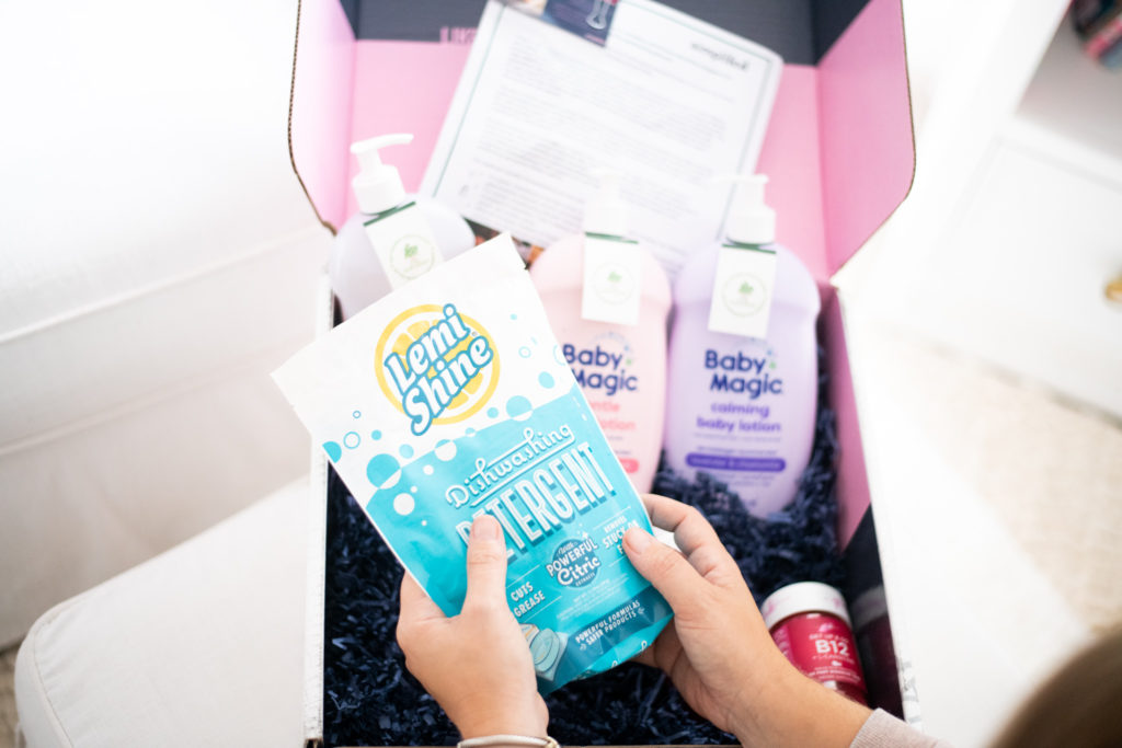 Baby Products by popular Ohio motherhood blog, Coffee Beans and Bobby Pins: image of woman sitting next to a box filled with a Baby Banana magic unicorn brush, Baby Banana Squish jelly fish, Lemi Shine detergent, and Baby Magic bath products, 
