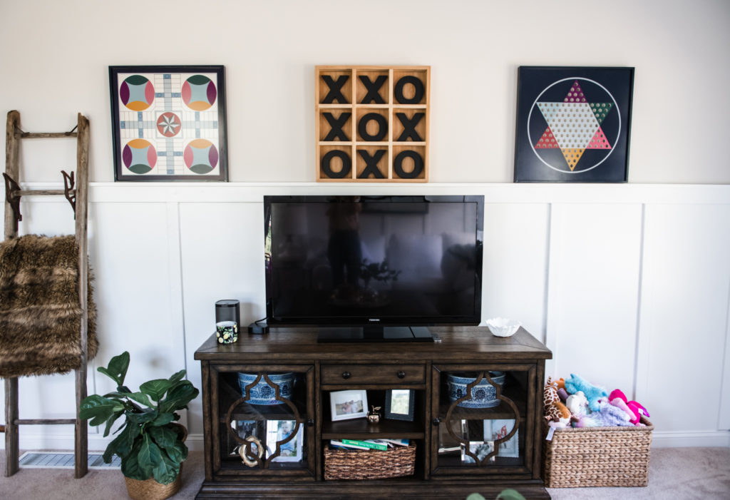 Art Display Ideas by popular Ohio life and style blog, Coffee Beans and Bobby Pins: image of a playroom decorated with Grandin Road game board trays, Grandin Road XOXO board, blanket ladder, fiddle leaf fig plant n a wicker basket, blue and white stripe rug, and a flat screen T.V.. 