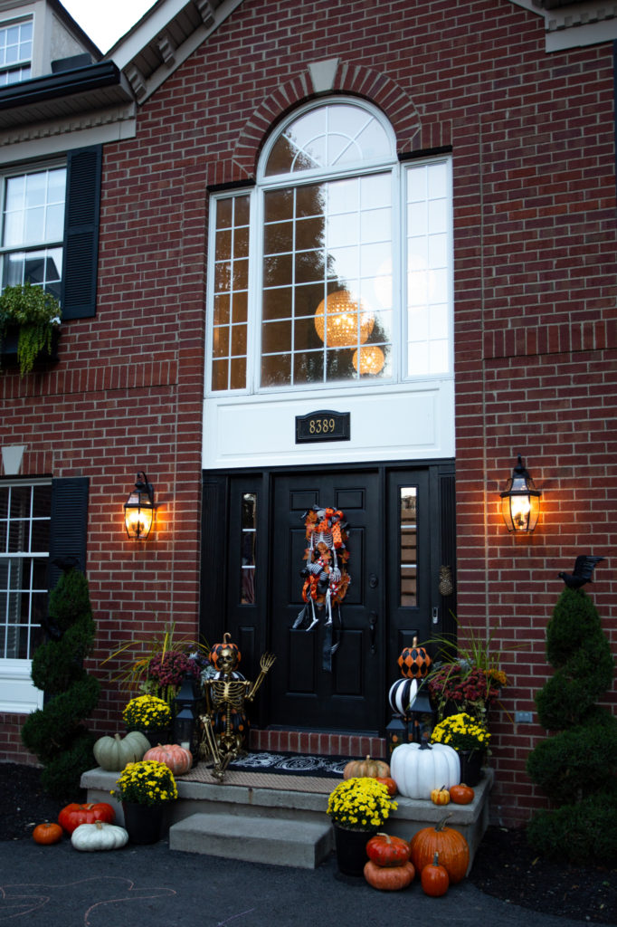 Halloween Front Porch by popular Ohio life and style blog, Coffee Beans and Bobby Pins: image of a front porch decorated with pumpkins, potted mums, a gold skeleton, Grandin Road Pumpkin decor. 