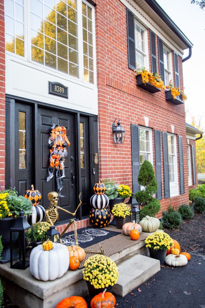 Halloween Front Porch by popular Ohio life and style blog, Coffee Beans and Bobby Pins: image of a front porch decorated with pumpkins, potted mums, a gold skeleton, Grandin Road Pumpkin decor. 