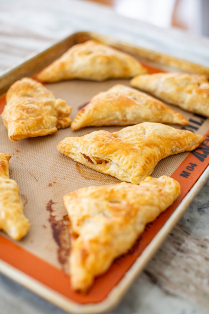 Easy Apple Turnovers by popular Ohio lifestyle blog, Coffee Beans and Bobby Pins: image of apple turnovers on a baking sheet. 