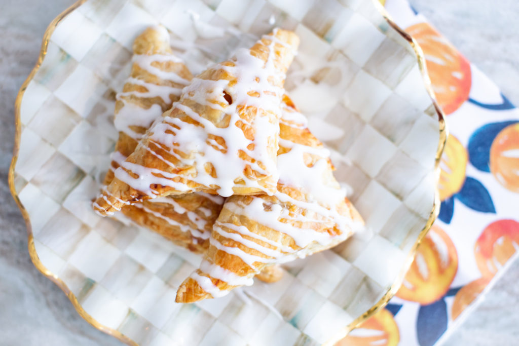 Easy Apple Turnovers by popular Ohio lifestyle blog, Coffee Beans and Bobby Pins: image of apple turnovers on checkered pattern plate. 