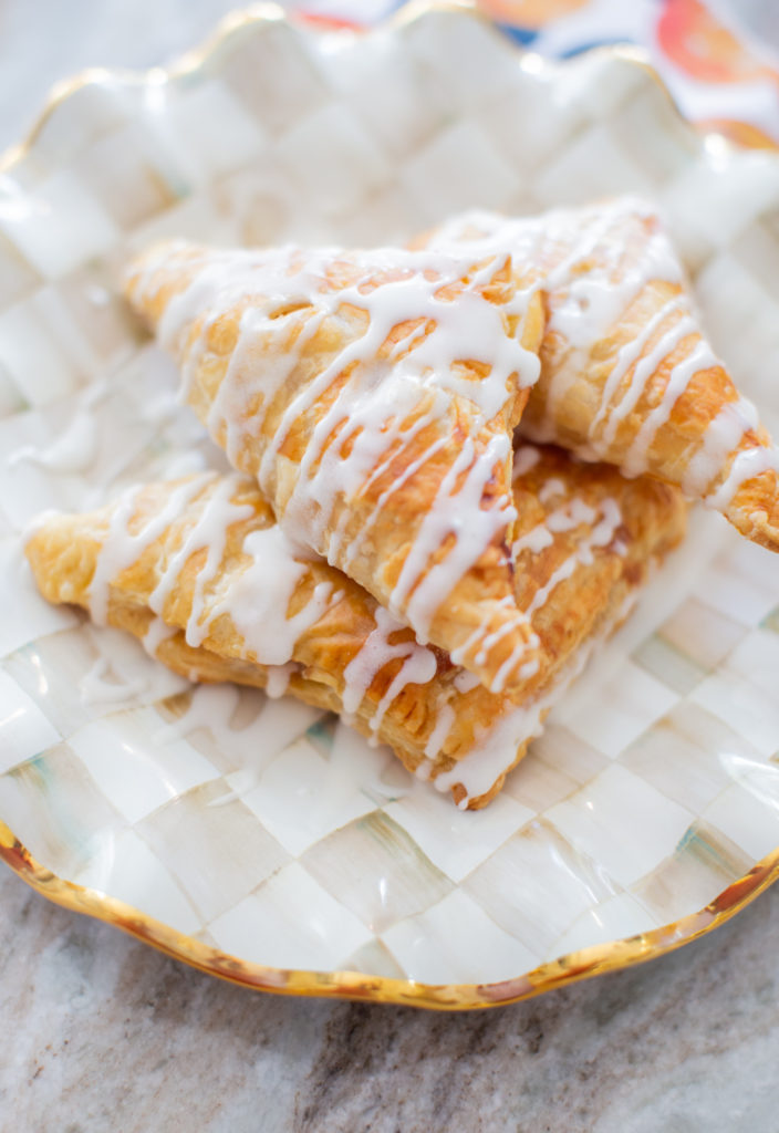 Easy Apple Turnovers by popular Ohio lifestyle blog, Coffee Beans and Bobby Pins: image of apple turnovers on checkered pattern plate. 