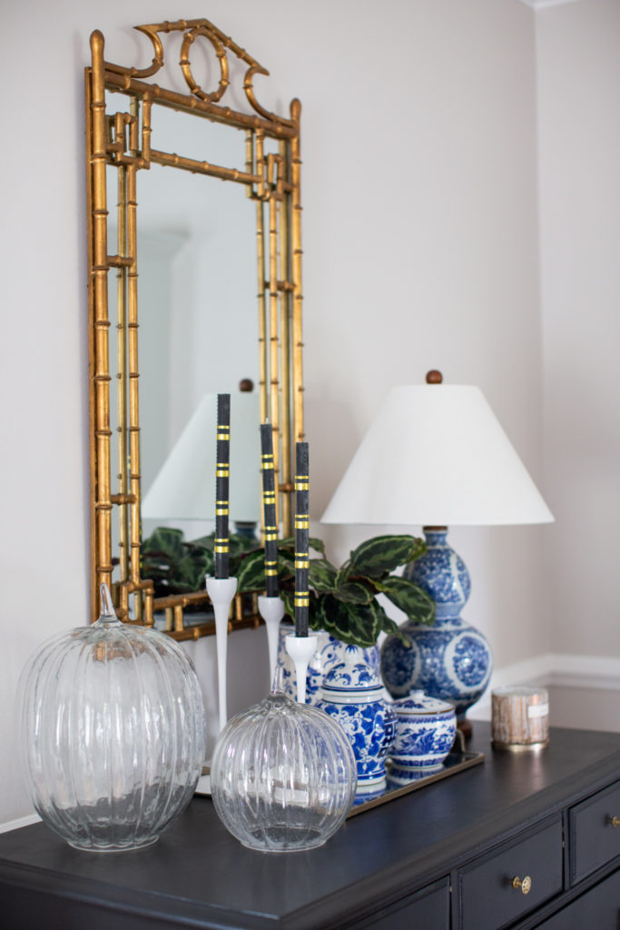 Home Tour by popular Ohio lifestyle blog, Coffee Beans and Bobby Pins: image of a gold bamboo frame mirror, blue and white china, clear glass pumpkins, and white candlestick holders with black and gold strip candles. 