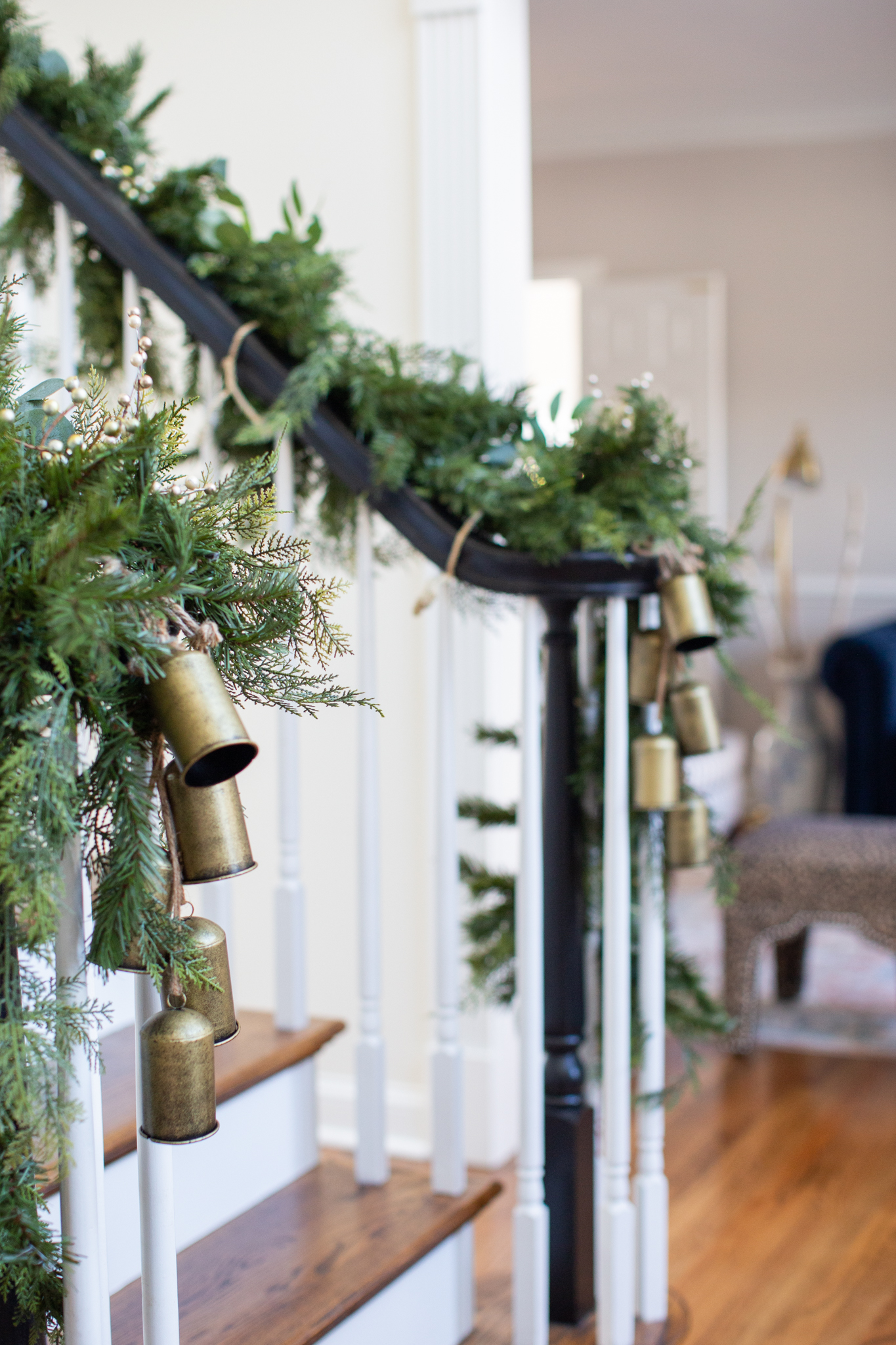 Christmas Home Decor Ideas by popular Ohio life and style blog, Coffee Beans and Bobby Pins: image of a entry way decorated with garland, cattle bells, and a Christmas wreath. 