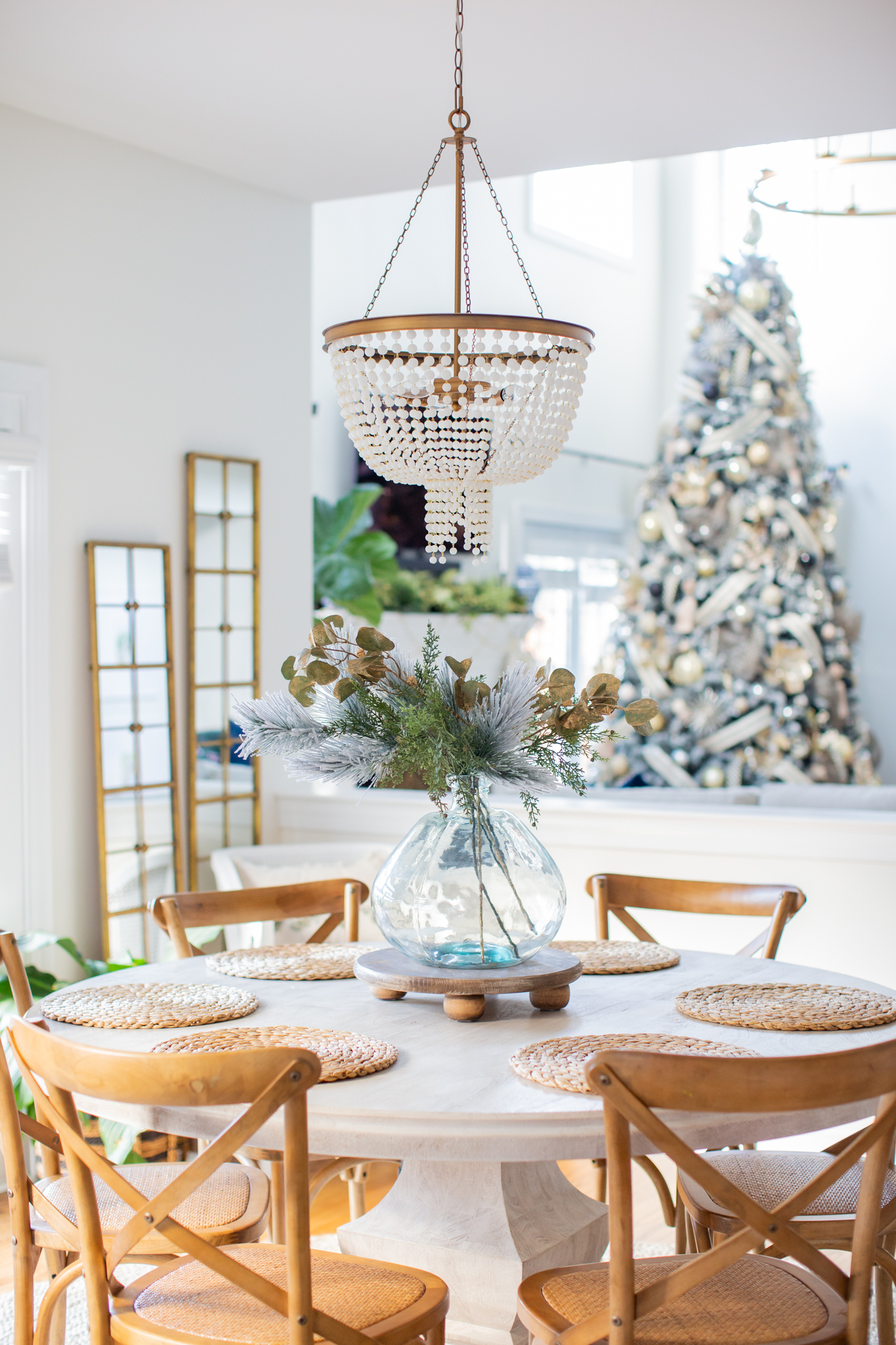 Christmas Home Tour by popular Ohio life and style blog, Coffee Beans and Bobby Pins: image of a table set with a Christmas center piece of pine boughs and eucalyptus stems. 