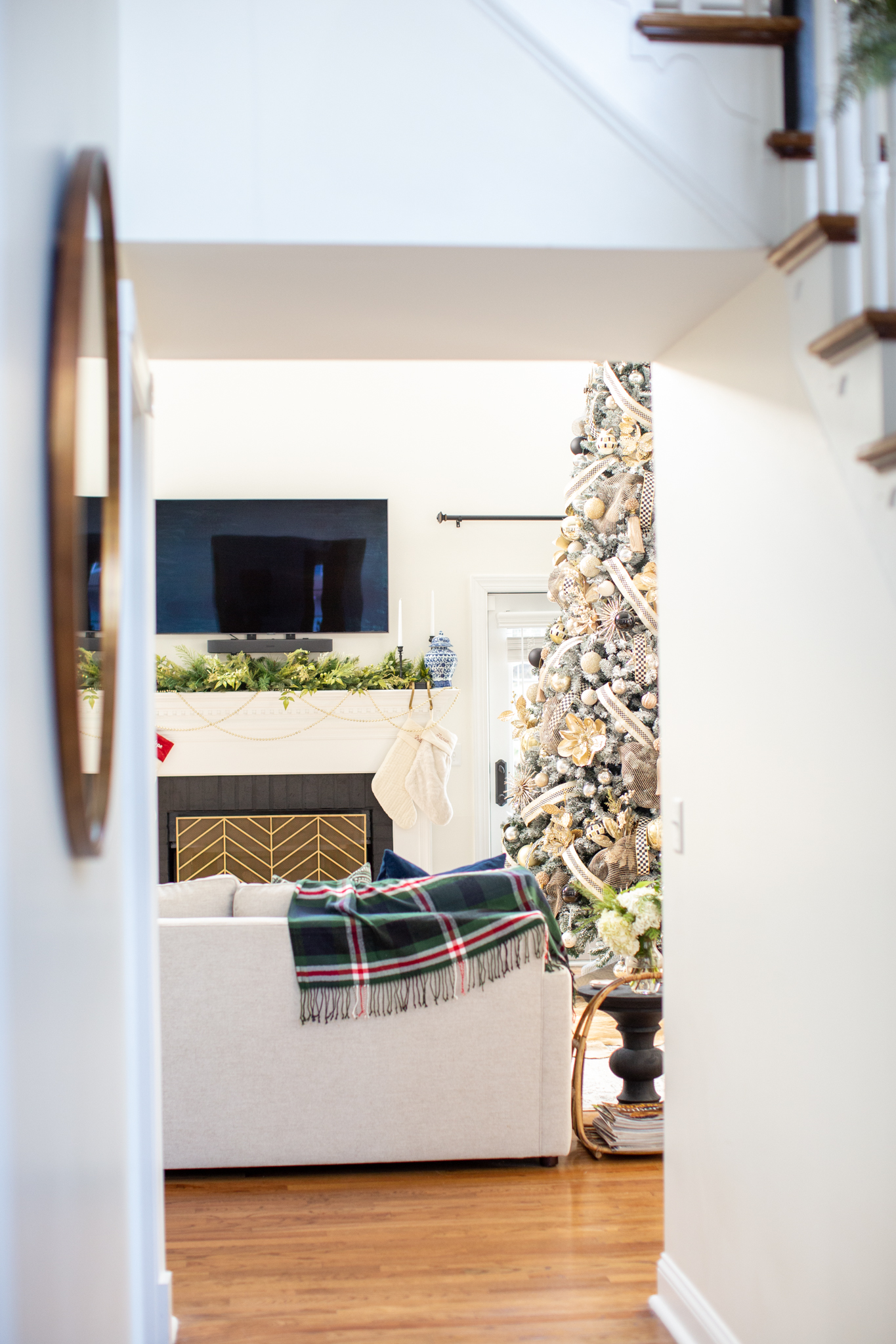 Christmas Home Tour by popular Ohio life and style blog, Coffee Beans and Bobby Pins: image of a black and gold flocked Christmas tree next to a fireplace with white stockings hanging from it. 