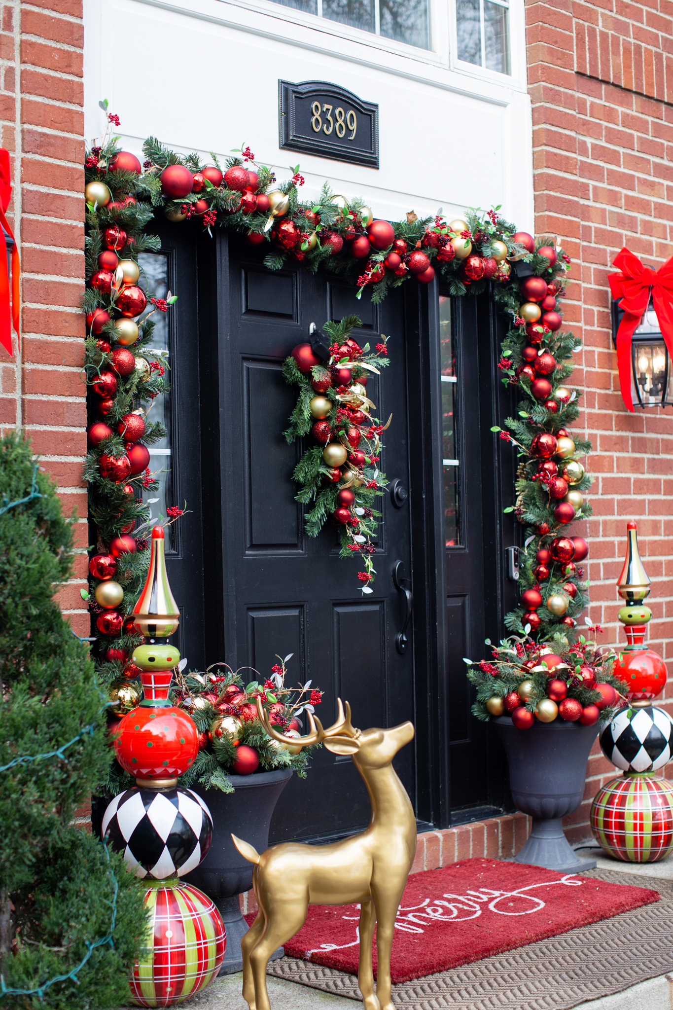 Holiday Decor by popular Ohio life and style blog, Coffee Beans and Bobby Pins: image of a house decorated with wreaths, red ribbons, poinsettias, and an ornament garland. 