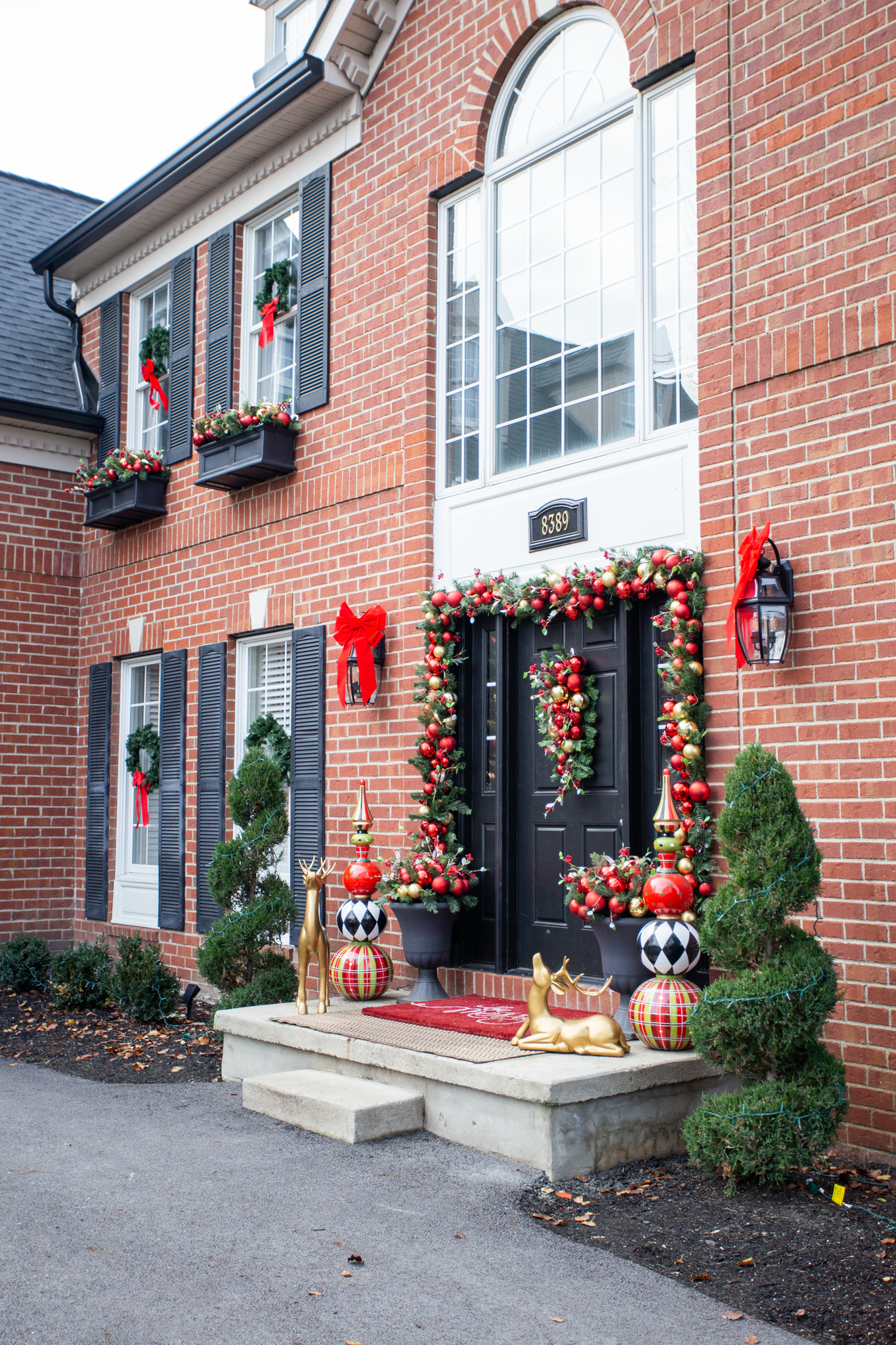 Holiday Decor by popular Ohio life and style blog, Coffee Beans and Bobby Pins: image of a house decorated with wreaths, red ribbons, poinsettias, and an ornament garland. 