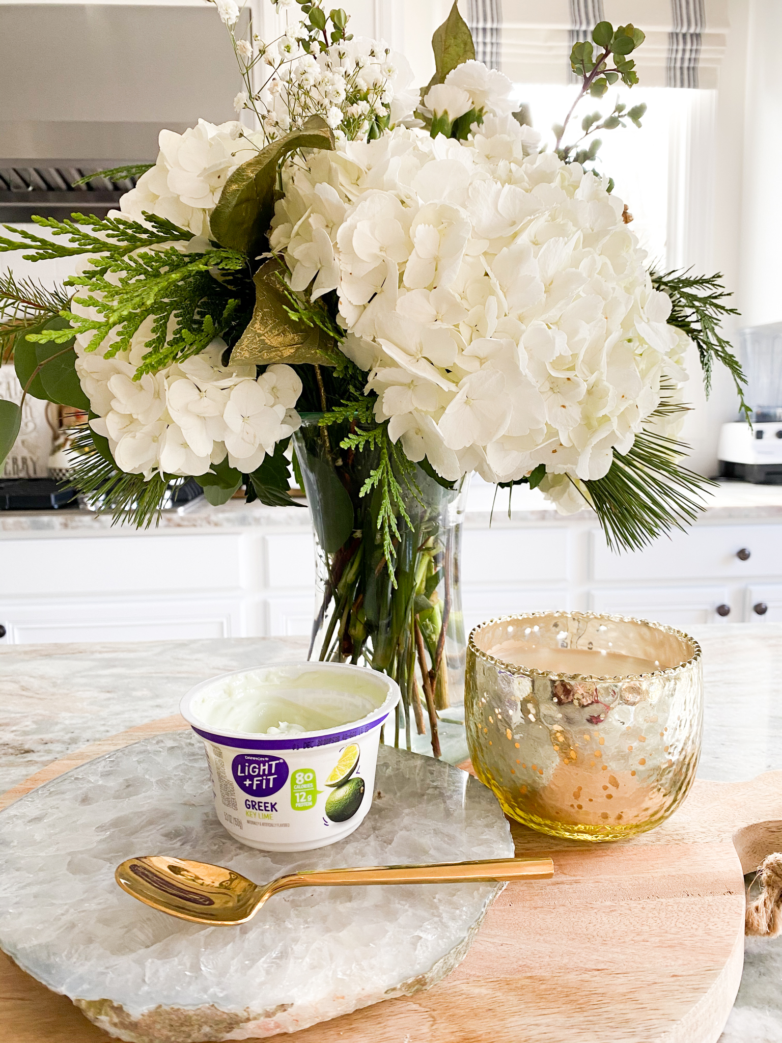 Making Goals by popular Ohio lifestyle blog, Coffee Beans and Bobby Pins: image of Danon Light + Fit Greek yogurt cup next to a gold spoon, vase of white flowers, and a gold candle votive. 