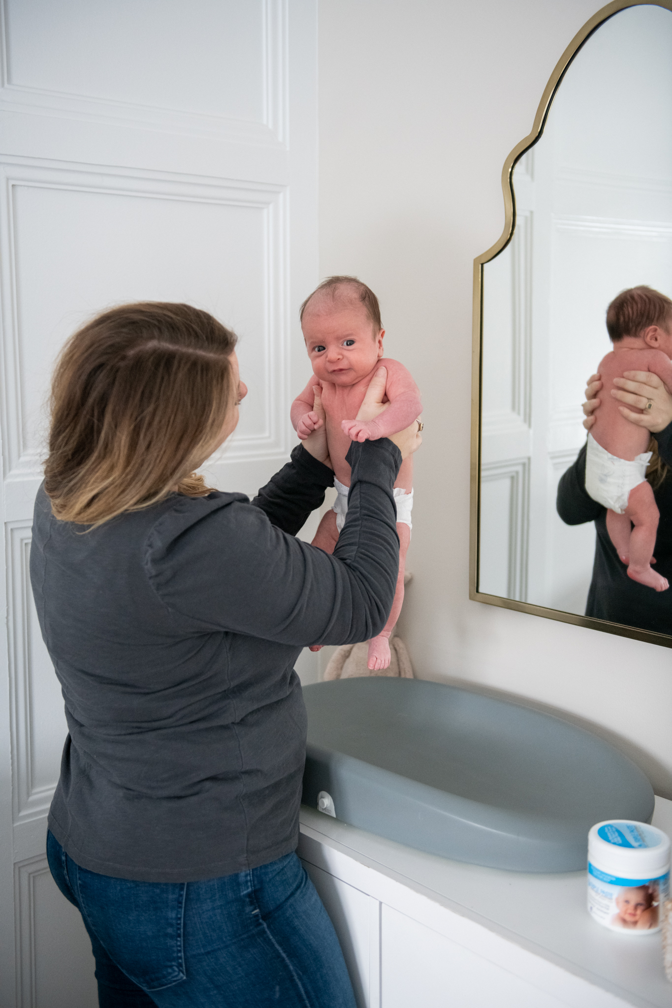 Diaper Rash Remedies by popular Ohio motherhood blog, Coffee Beans and Bobby Pins: image of a mom holding her one month old baby over a changing table. 